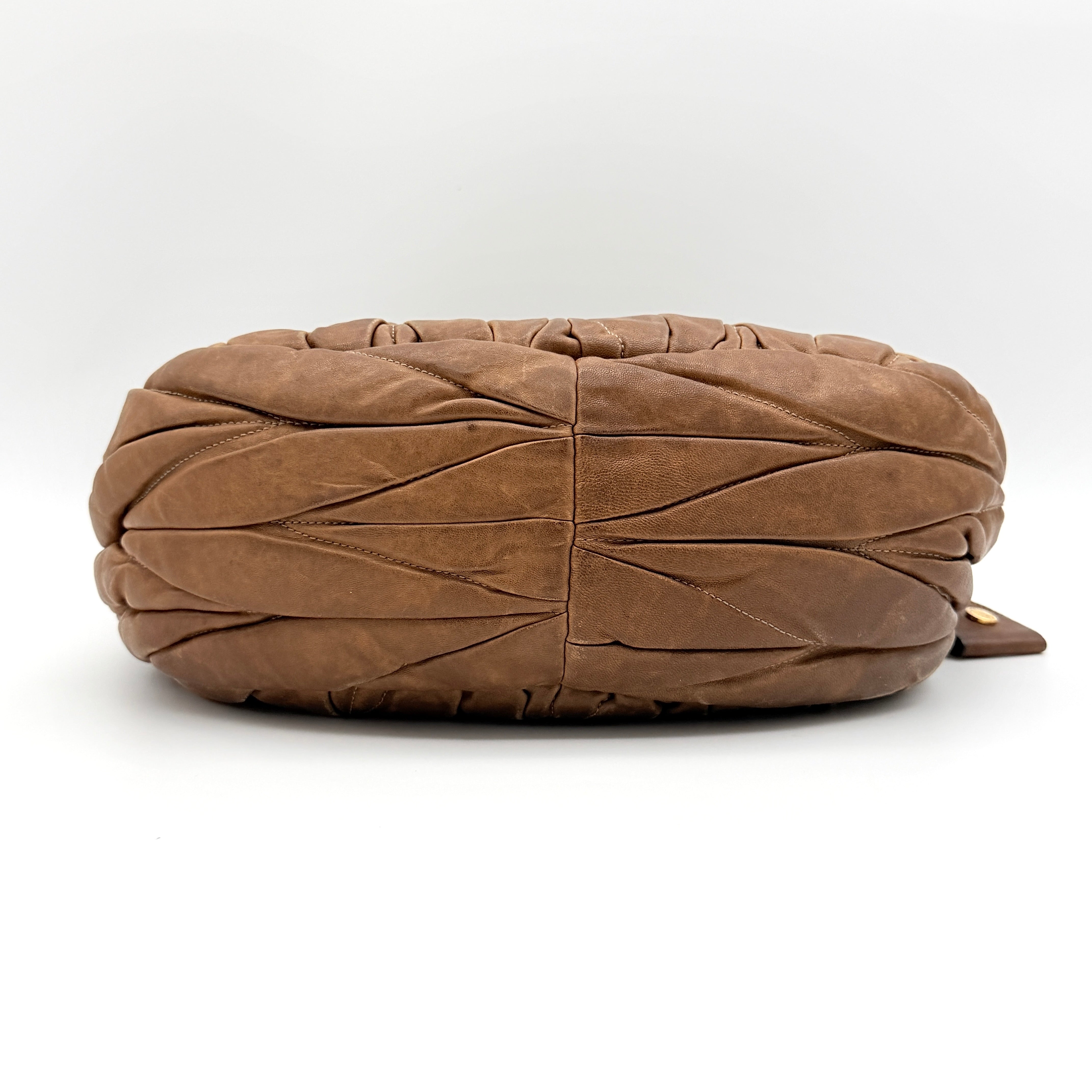 Miu Miu brown Matelasse Coffer Hobo bag with gold hardware, detachable strap, and dust bag displayed on a flat surface.