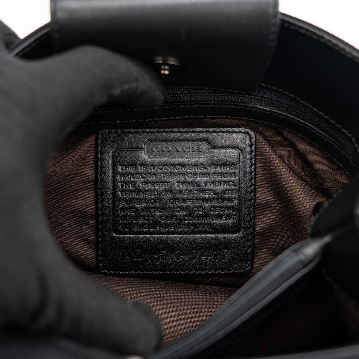 Coach Mercer tote bag in black nylon with leather handle and trim, presented against a white background.