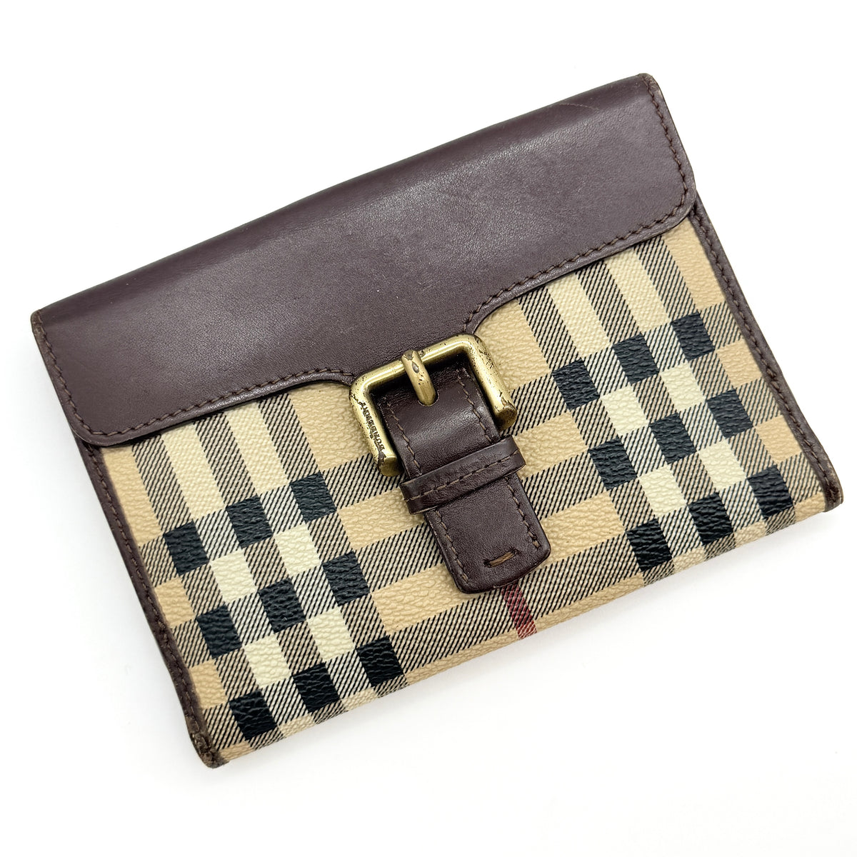 Burberry Nova Check wallet in beige and brown with leather trim and brass buckle detail photographed on white background.