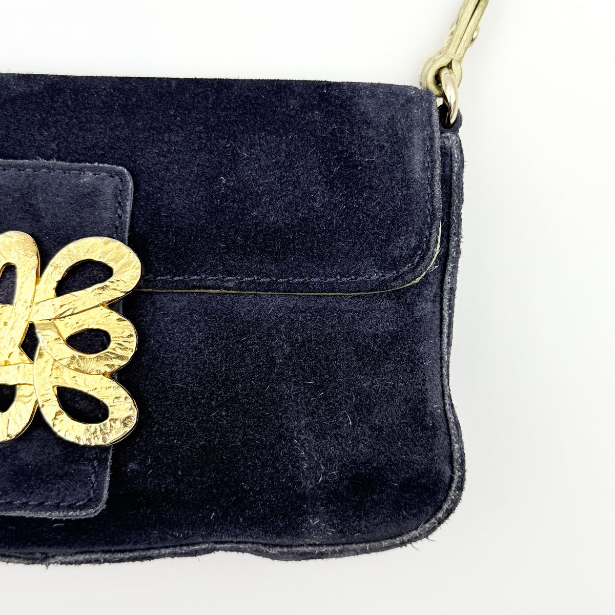 Navy blue suede Kate Spade baguette bag with floral gold hardware and gold-tone shoulder strap.