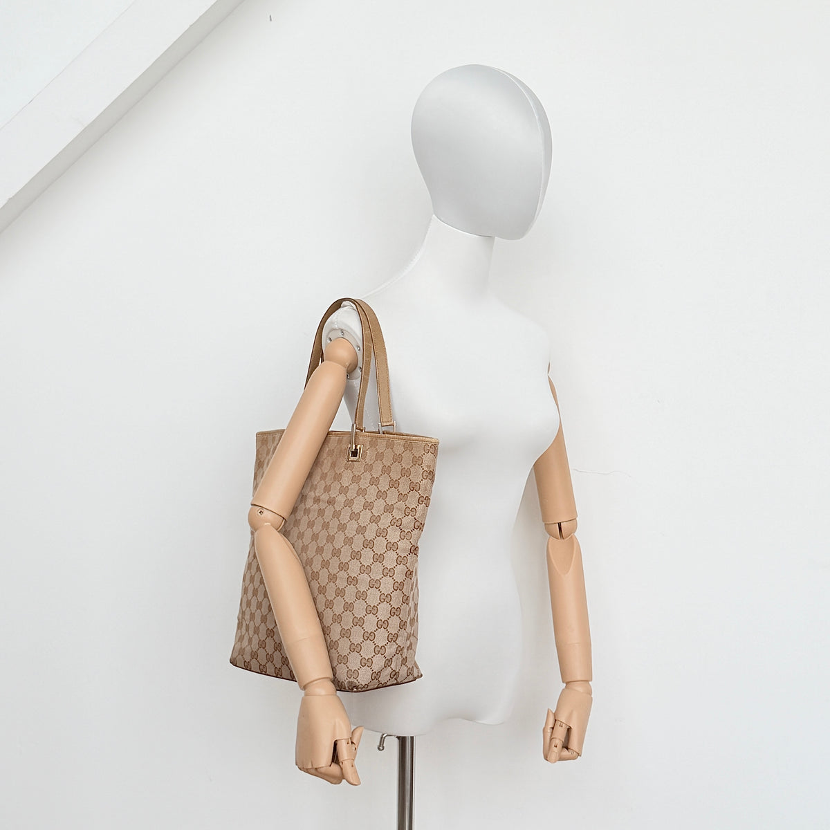 Front-facing Gucci GG Monogram Tote Bag in beige canvas with brown leather trim and double handles.