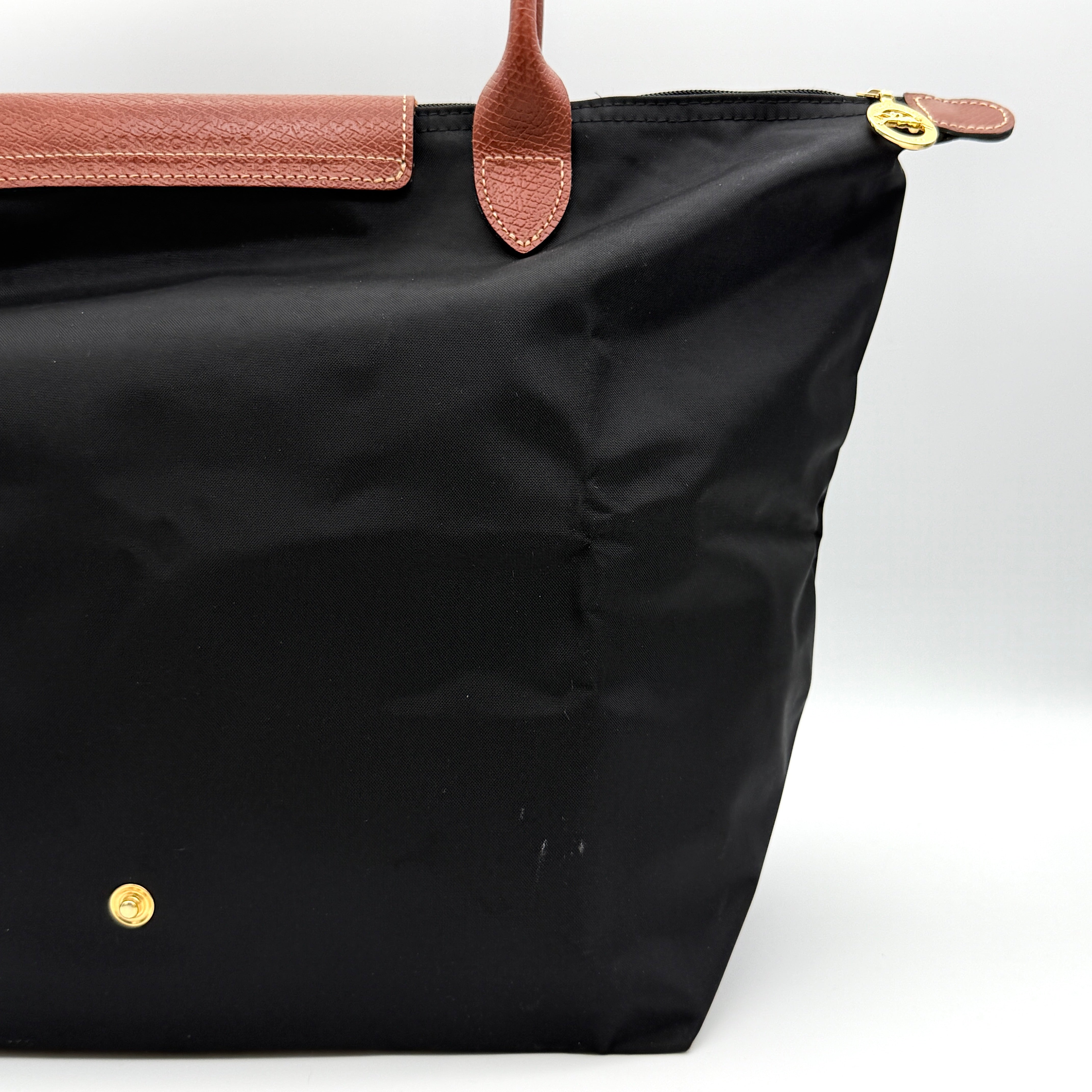 Longchamp Le Pliage Original Tote Bag in black with brown leather handles and flap, photographed against a white background.