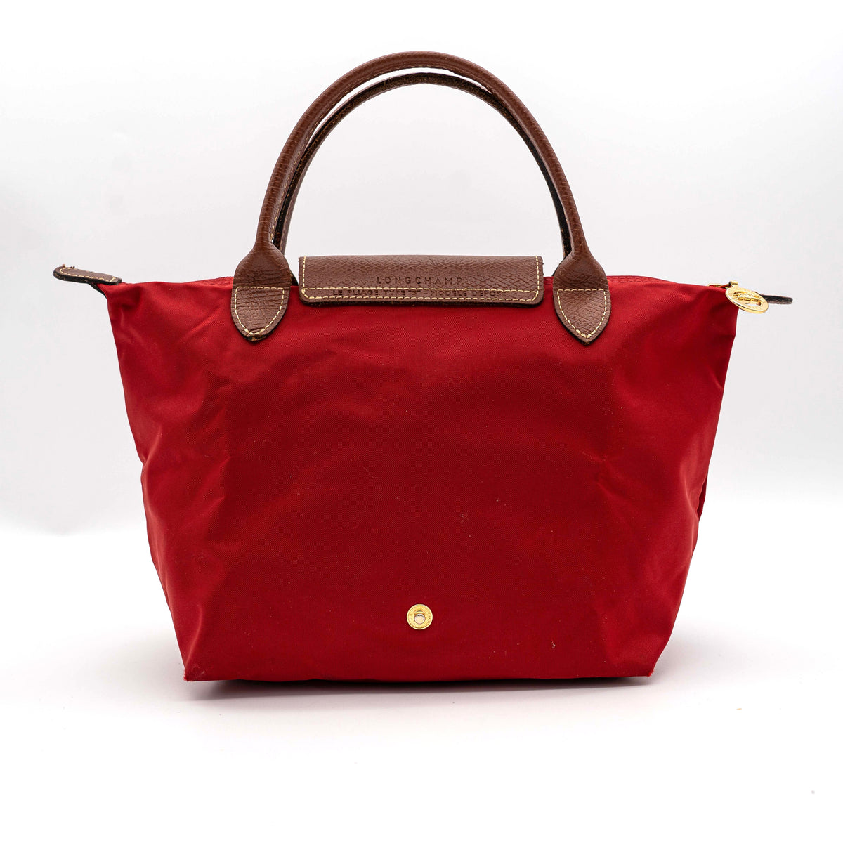 Longchamp Le Pliage handbag in red nylon with brown leather handles and gold-tone accents, photographed on a white background.