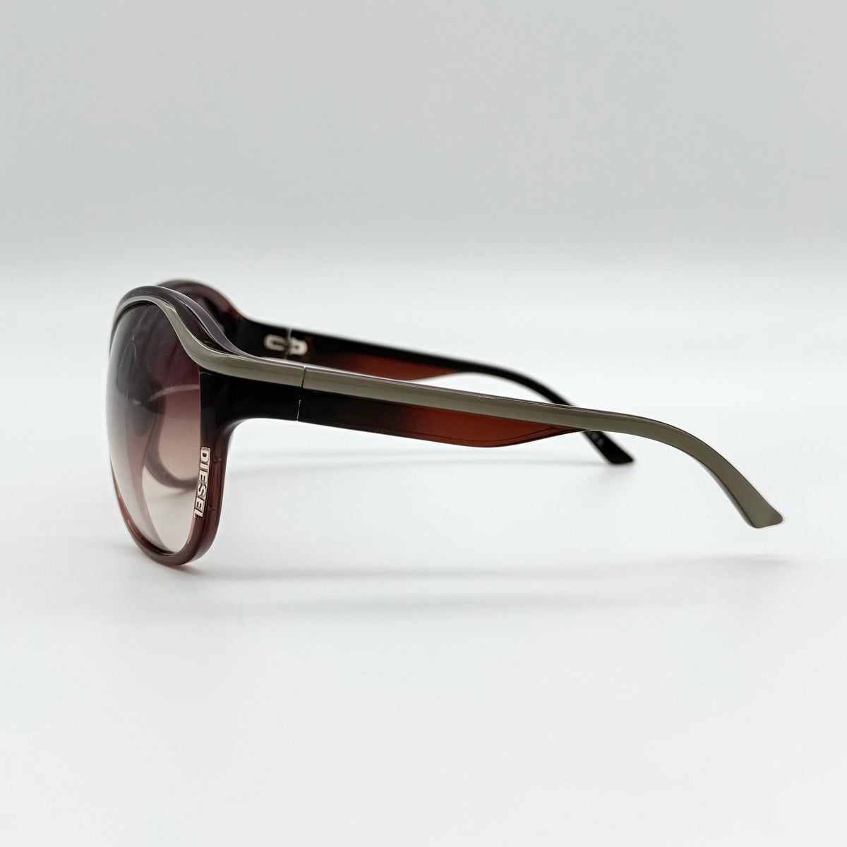 Diesel DS0094 sunglasses in gradient brown with oversized round lenses, shown with branded case and cleaning cloth.