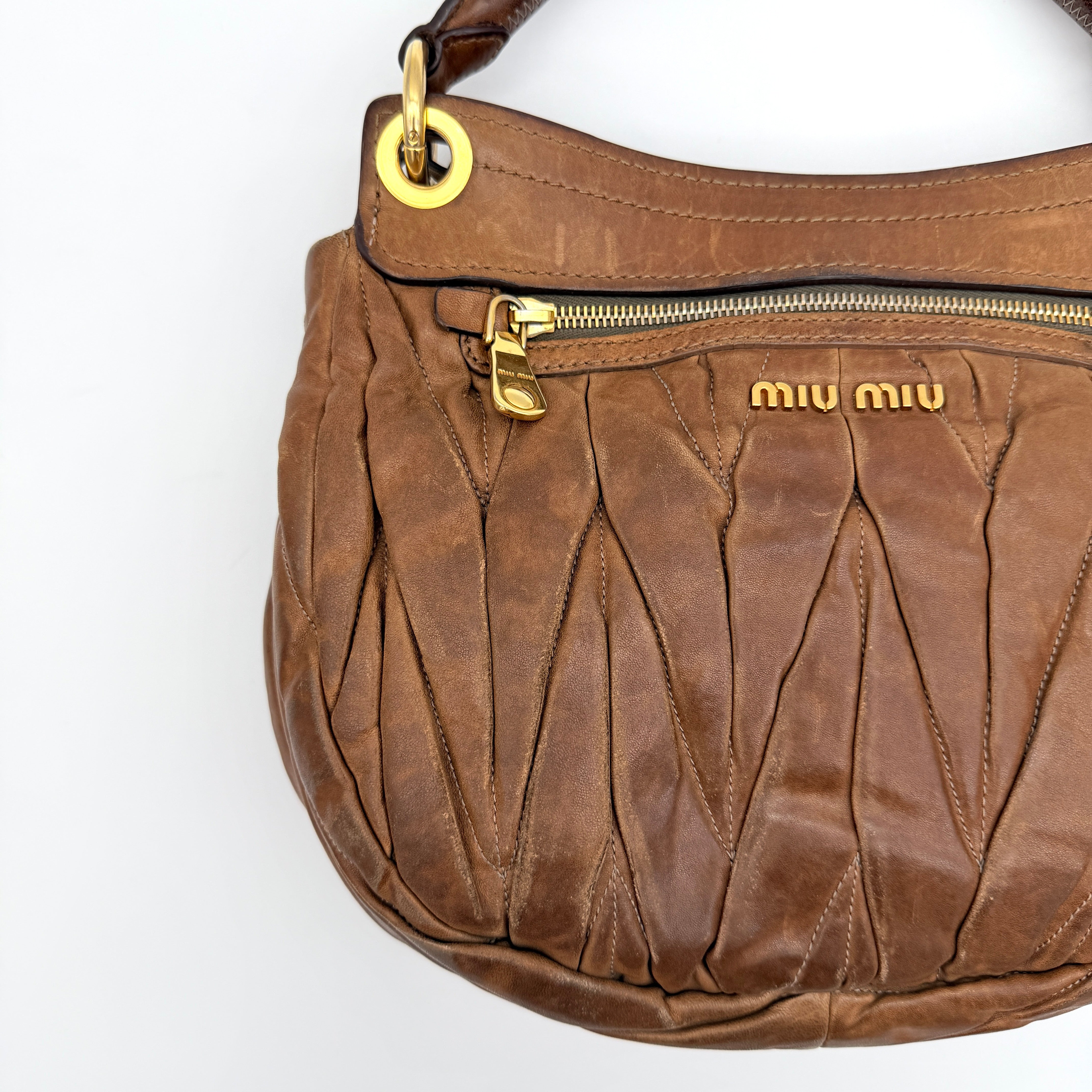 Miu Miu brown Matelasse Coffer Hobo bag with gold hardware, detachable strap, and dust bag displayed on a flat surface.