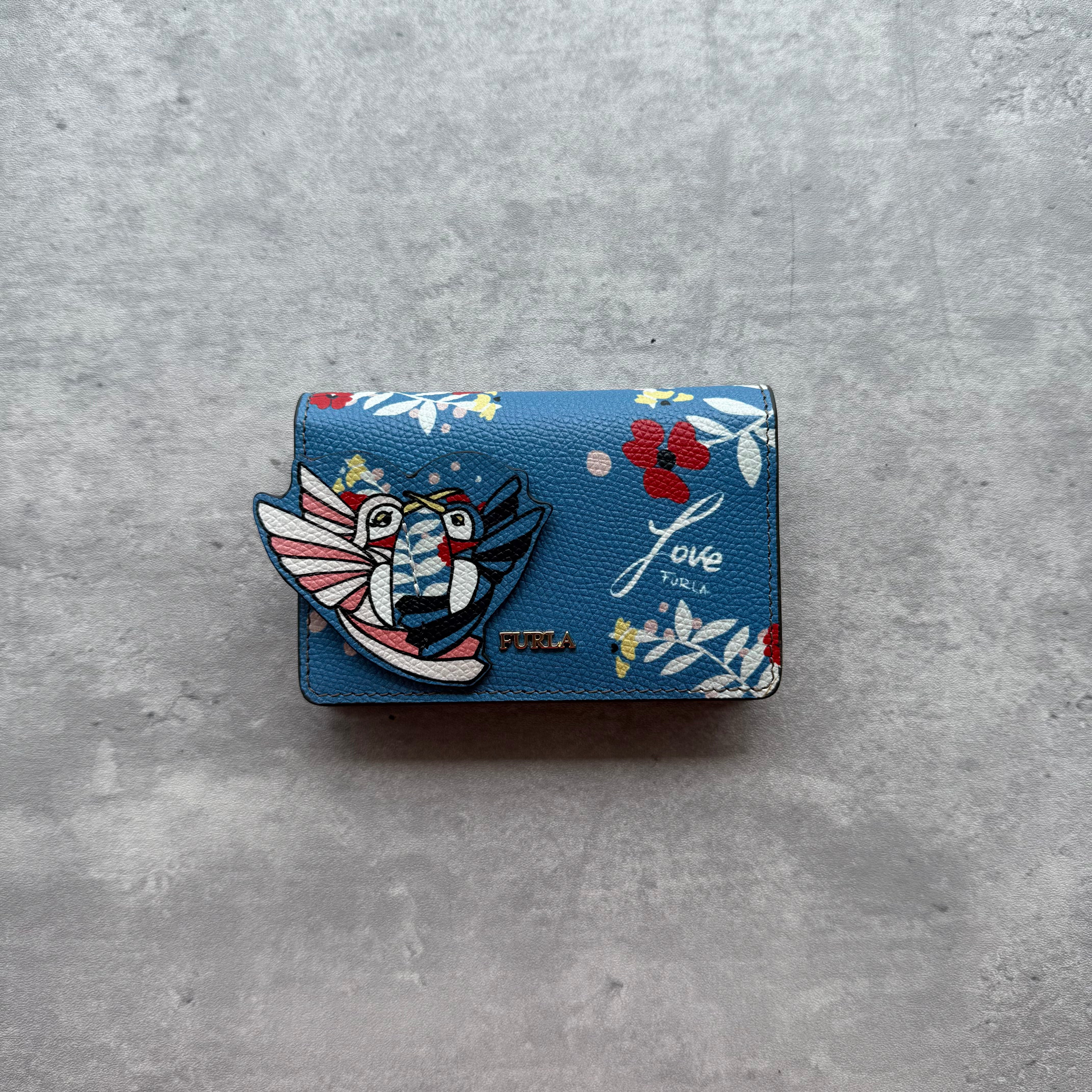 Furla 'Love Furla' Compact Wallet in multicolor printed leather with red interior and snap button closure.