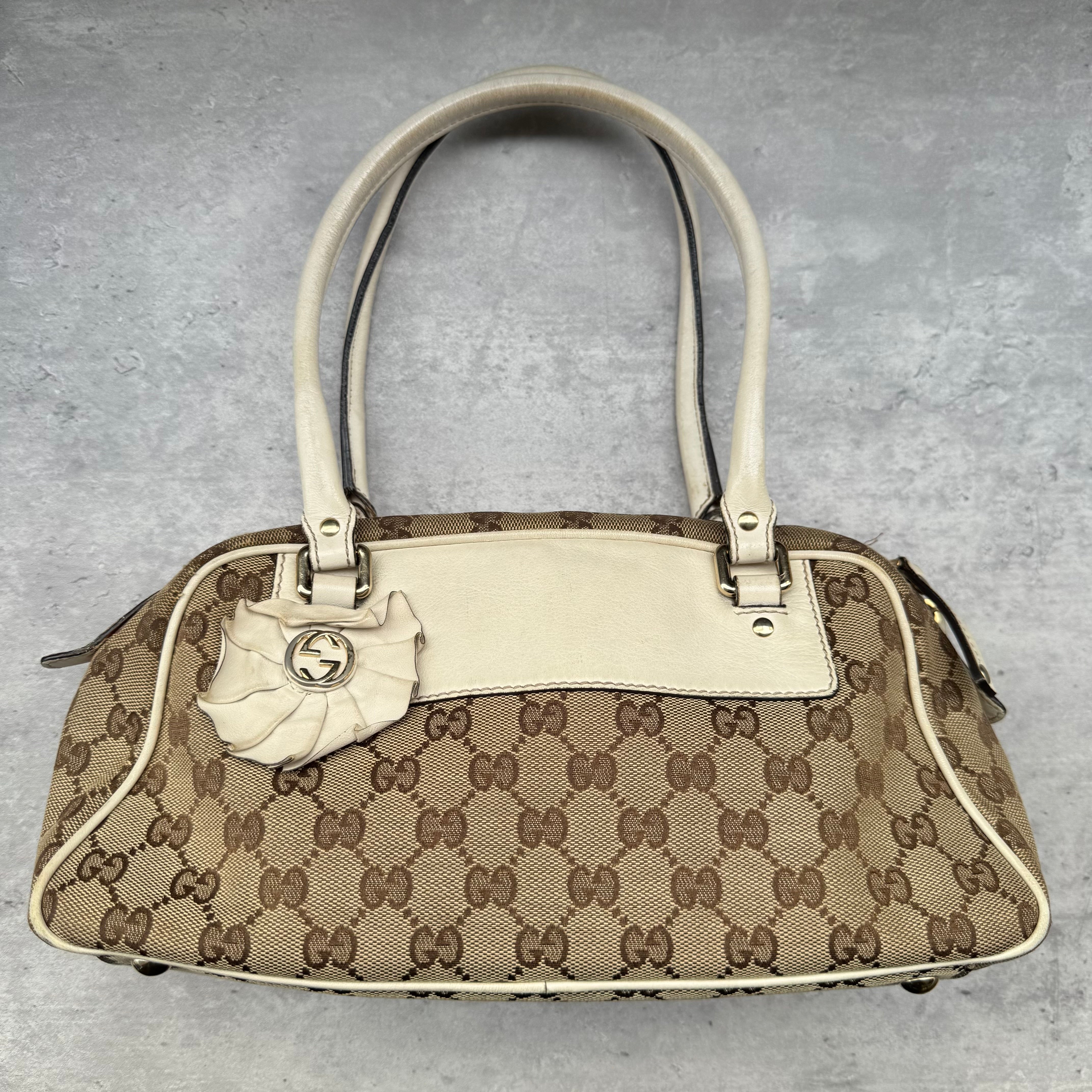 Gucci GG Canvas Trophy Boston Bag in beige monogram canvas with cream leather trim and floral GG emblem detail.