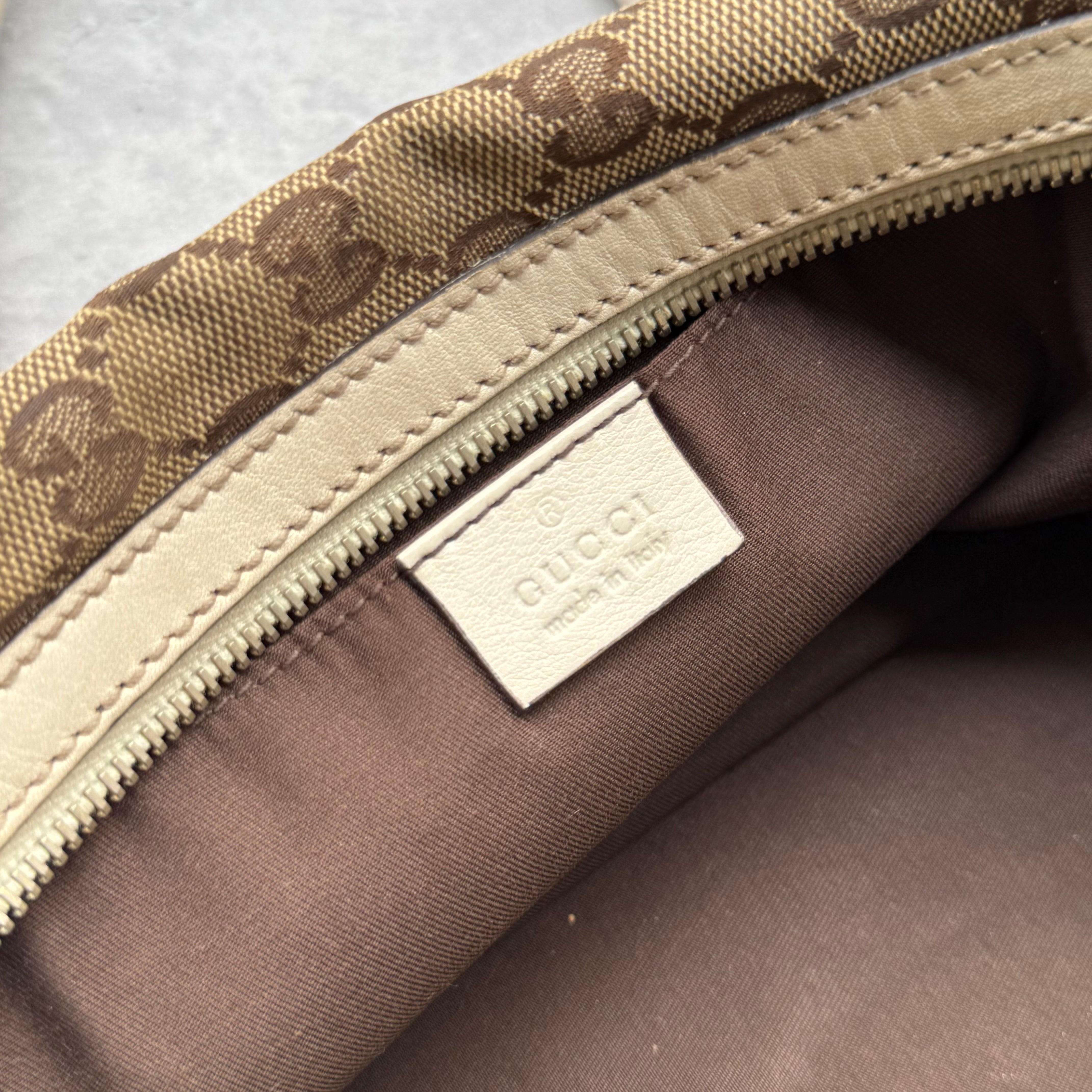 Gucci GG Canvas Trophy Boston Bag in beige monogram canvas with cream leather trim and floral GG emblem detail.