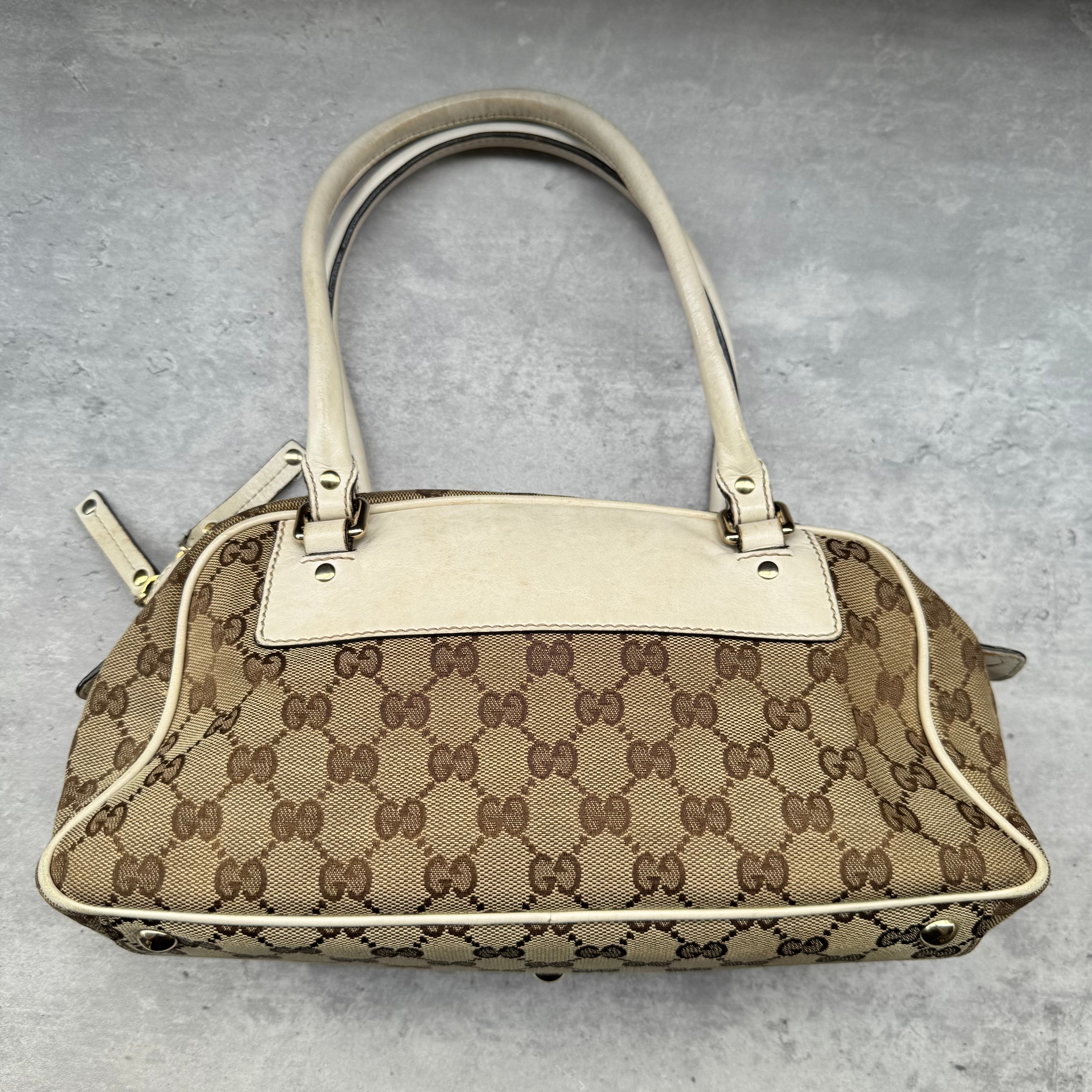 Gucci GG Canvas Trophy Boston Bag in beige monogram canvas with cream leather trim and floral GG emblem detail.