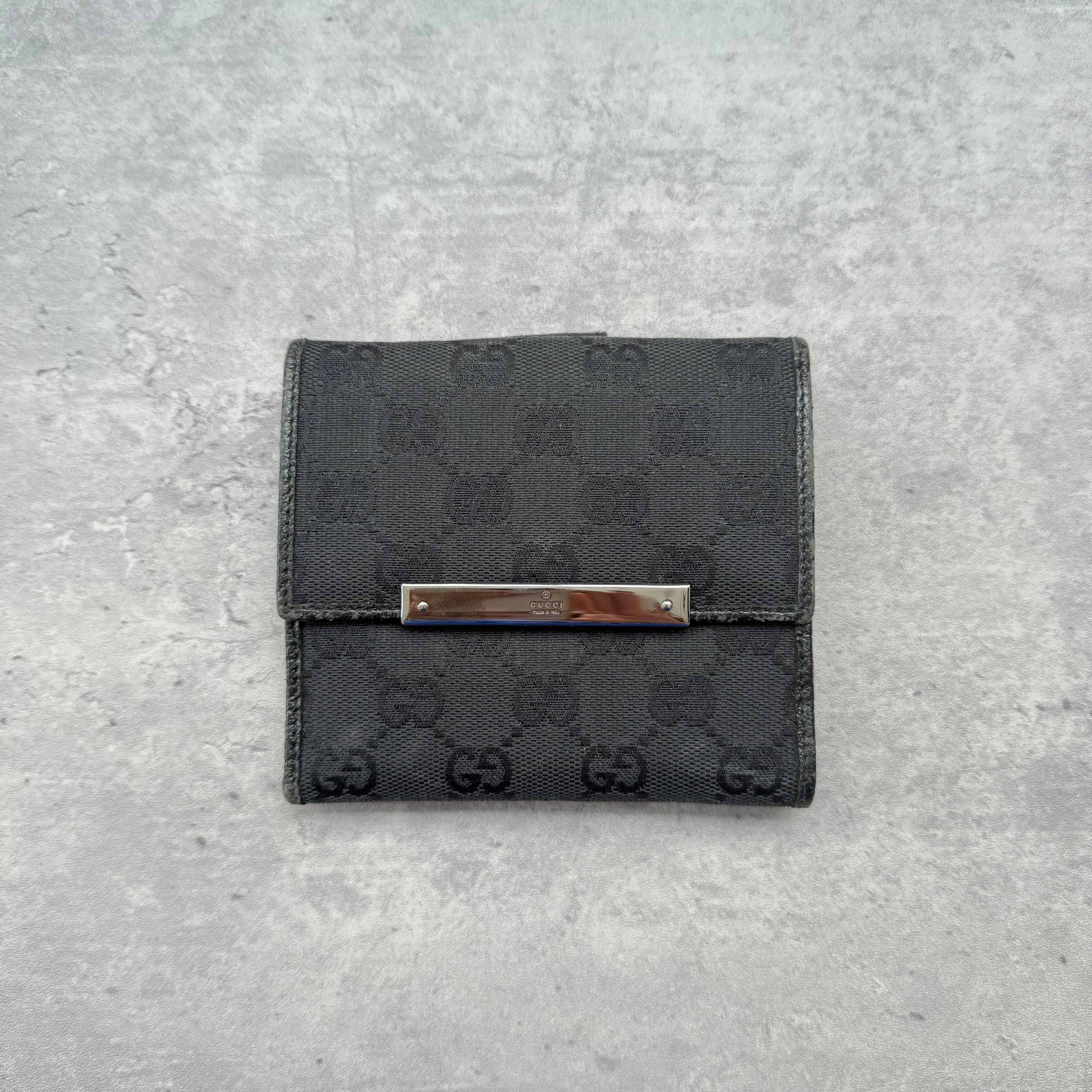 Gucci GG Monogram Compact Wallet Black, crafted from monogram canvas with leather trim, featuring silver-tone bar detail and organized interior.