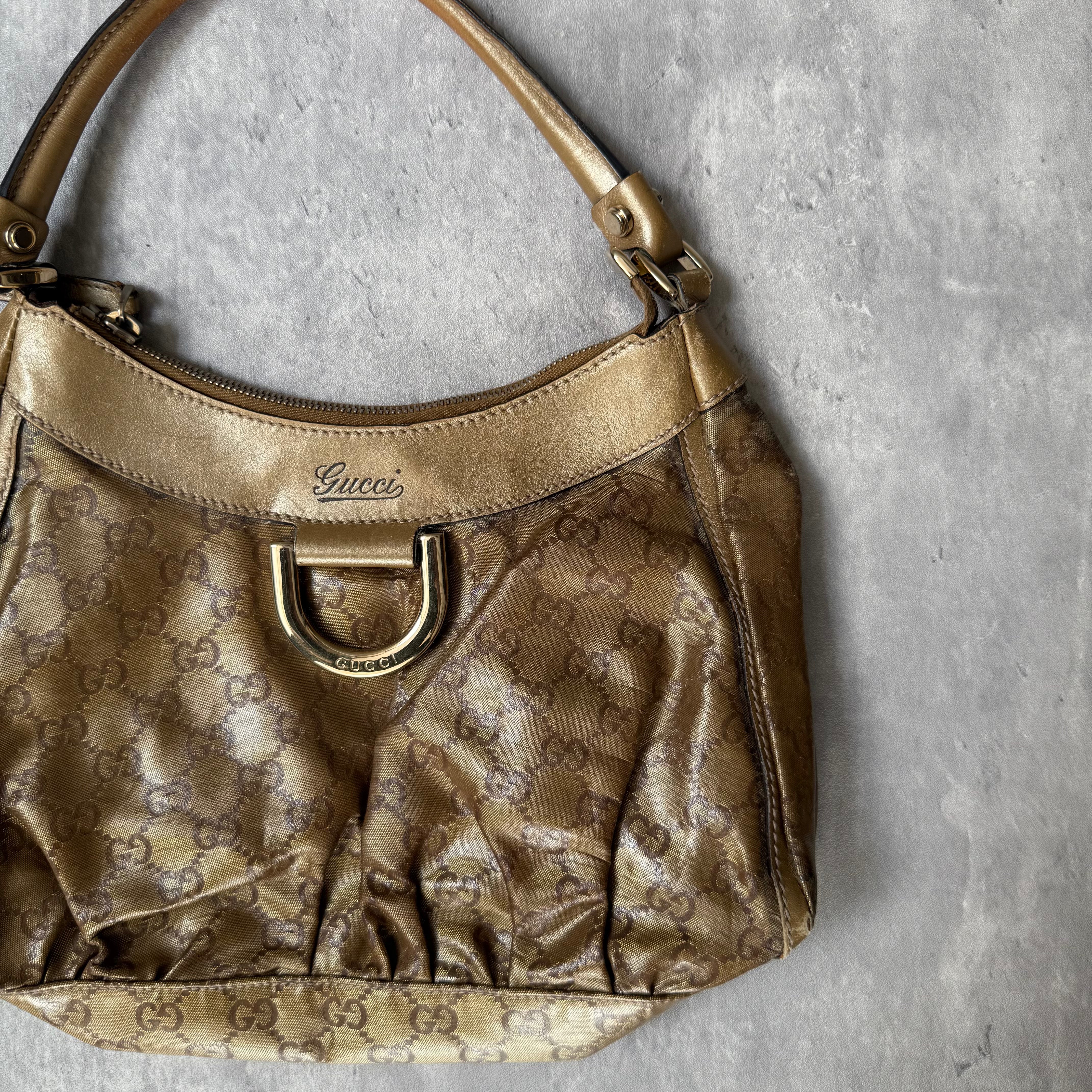 Gucci GG Monogram D-Ring Shoulder Bag in metallic gold with patent leather trim, pleated body, and gold-tone hardware.