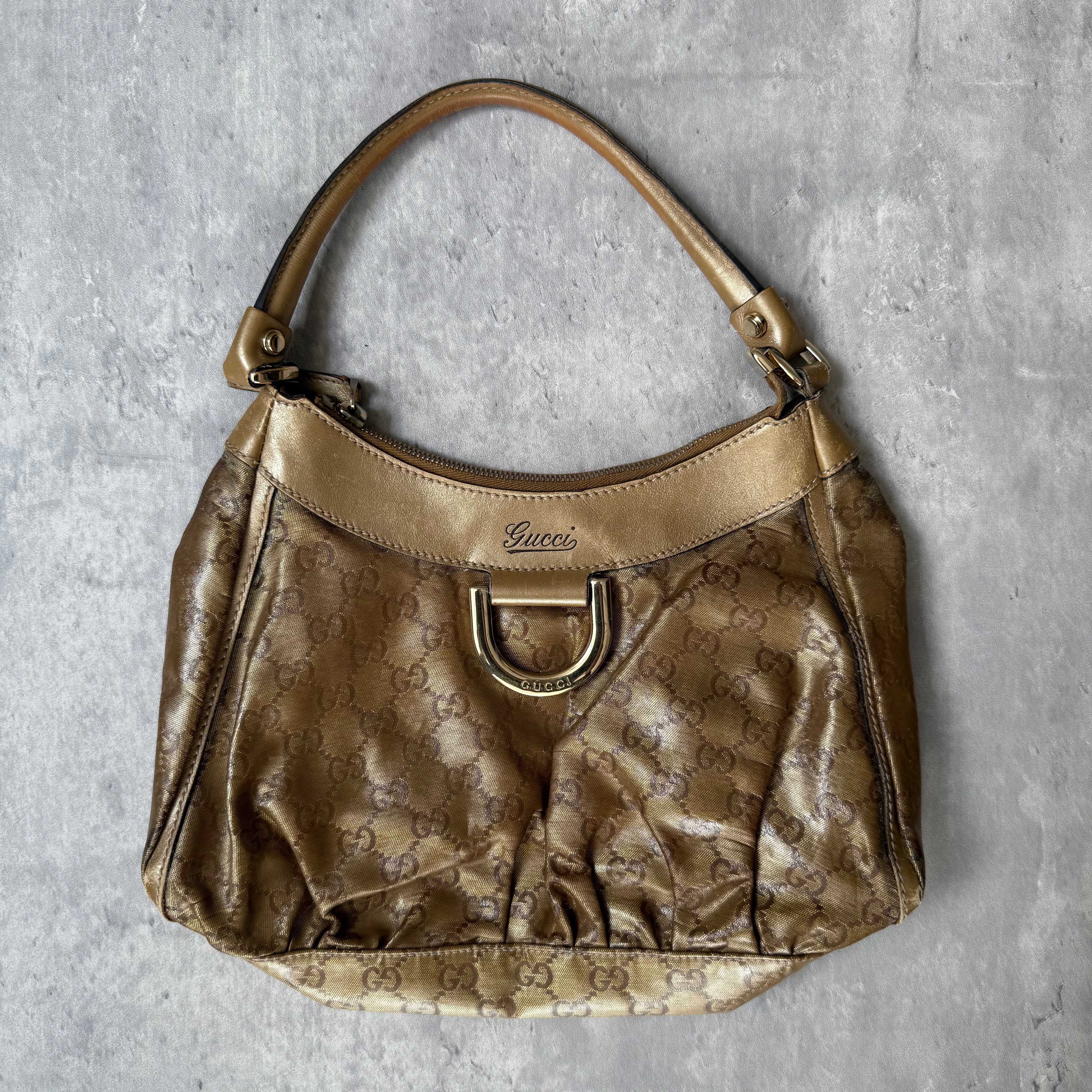 Gucci GG Monogram D-Ring Shoulder Bag in metallic gold with patent leather trim, pleated body, and gold-tone hardware.