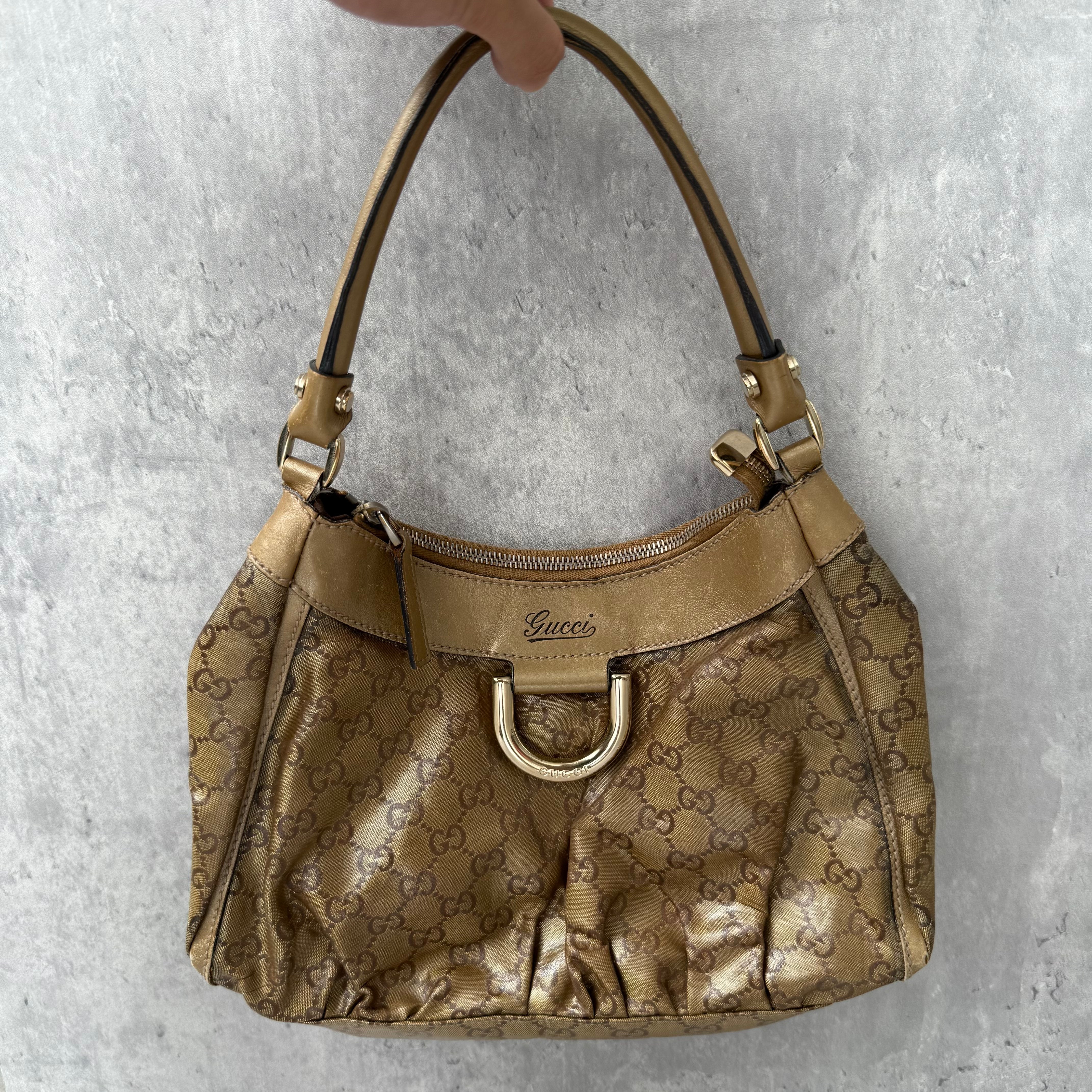 Gucci GG Monogram D-Ring Shoulder Bag in metallic gold with patent leather trim, pleated body, and gold-tone hardware.