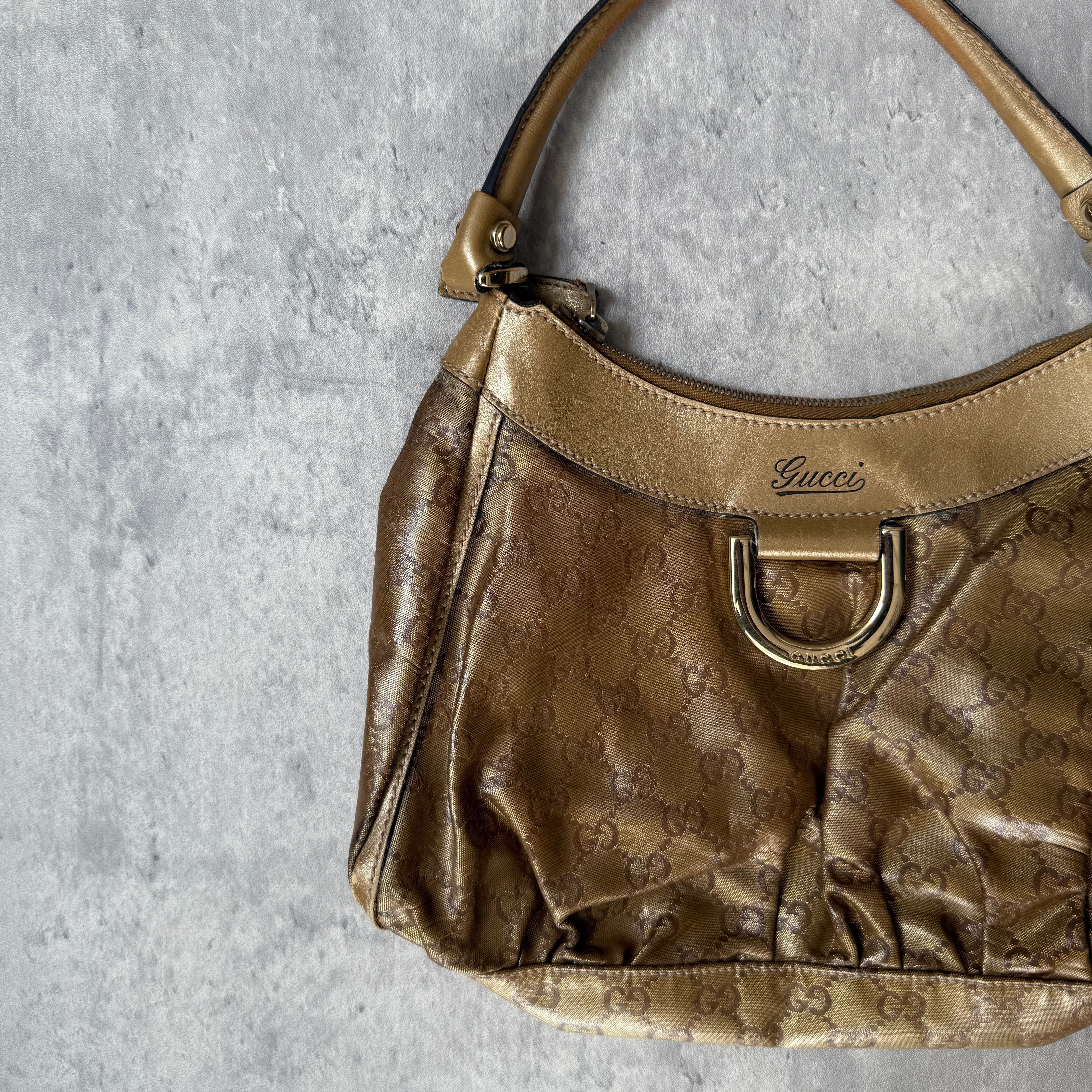 Gucci GG Monogram D-Ring Shoulder Bag in metallic gold with patent leather trim, pleated body, and gold-tone hardware.