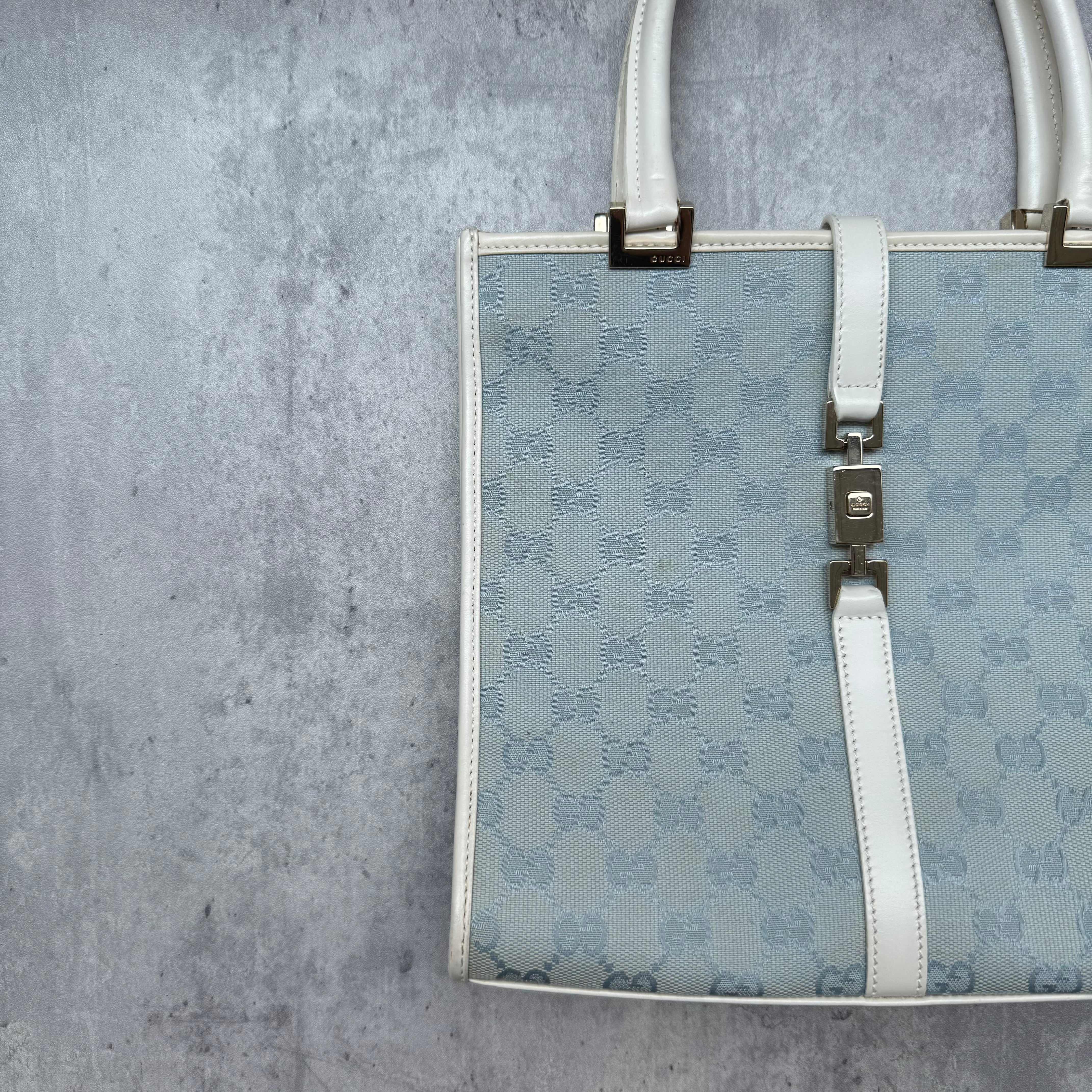 Gucci GG Monogram Jackie Shoulder Bag in light blue canvas with white leather trim, structured silhouette, and silver-tone piston lock.