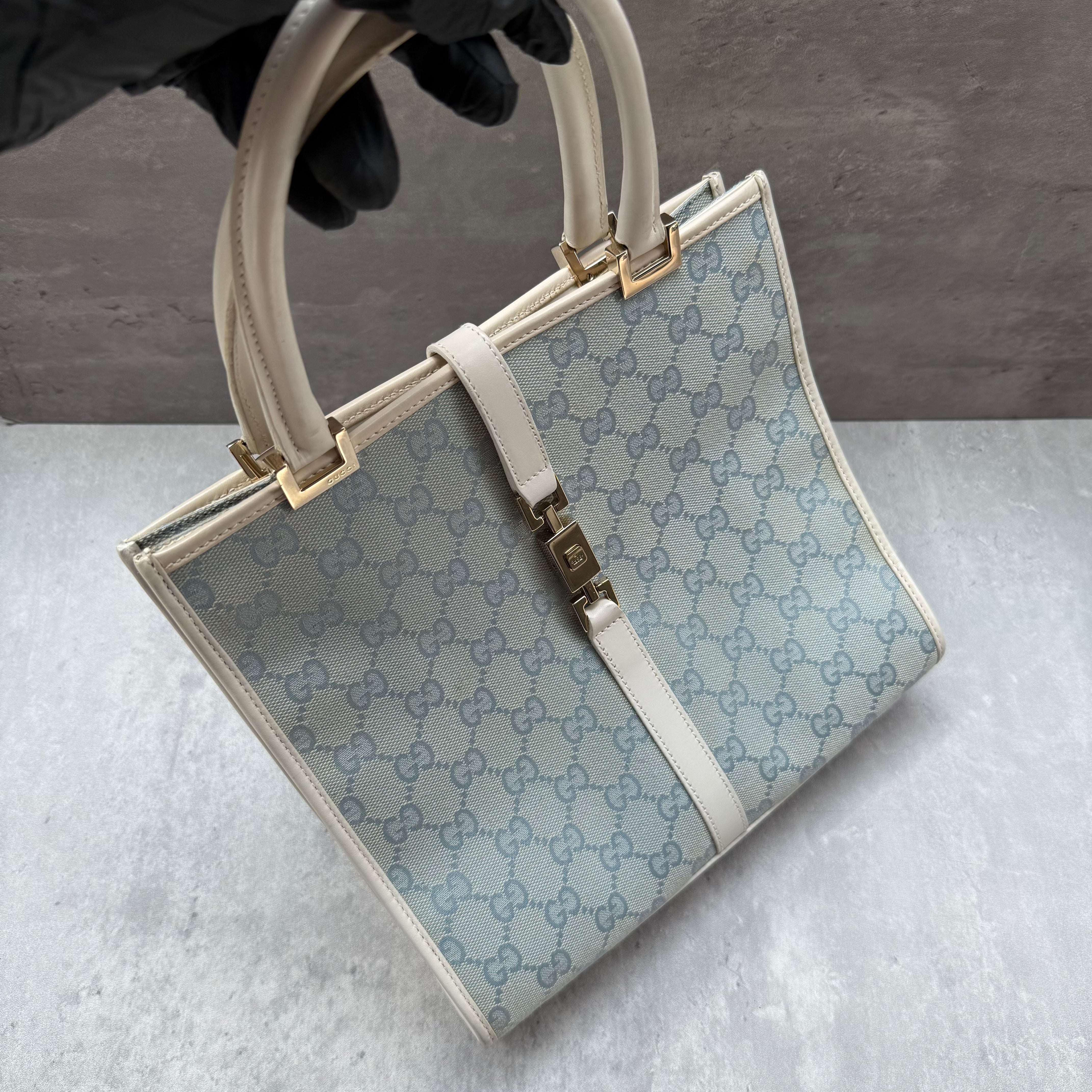 Gucci GG Monogram Jackie Shoulder Bag in light blue canvas with white leather trim, structured silhouette, and silver-tone piston lock.