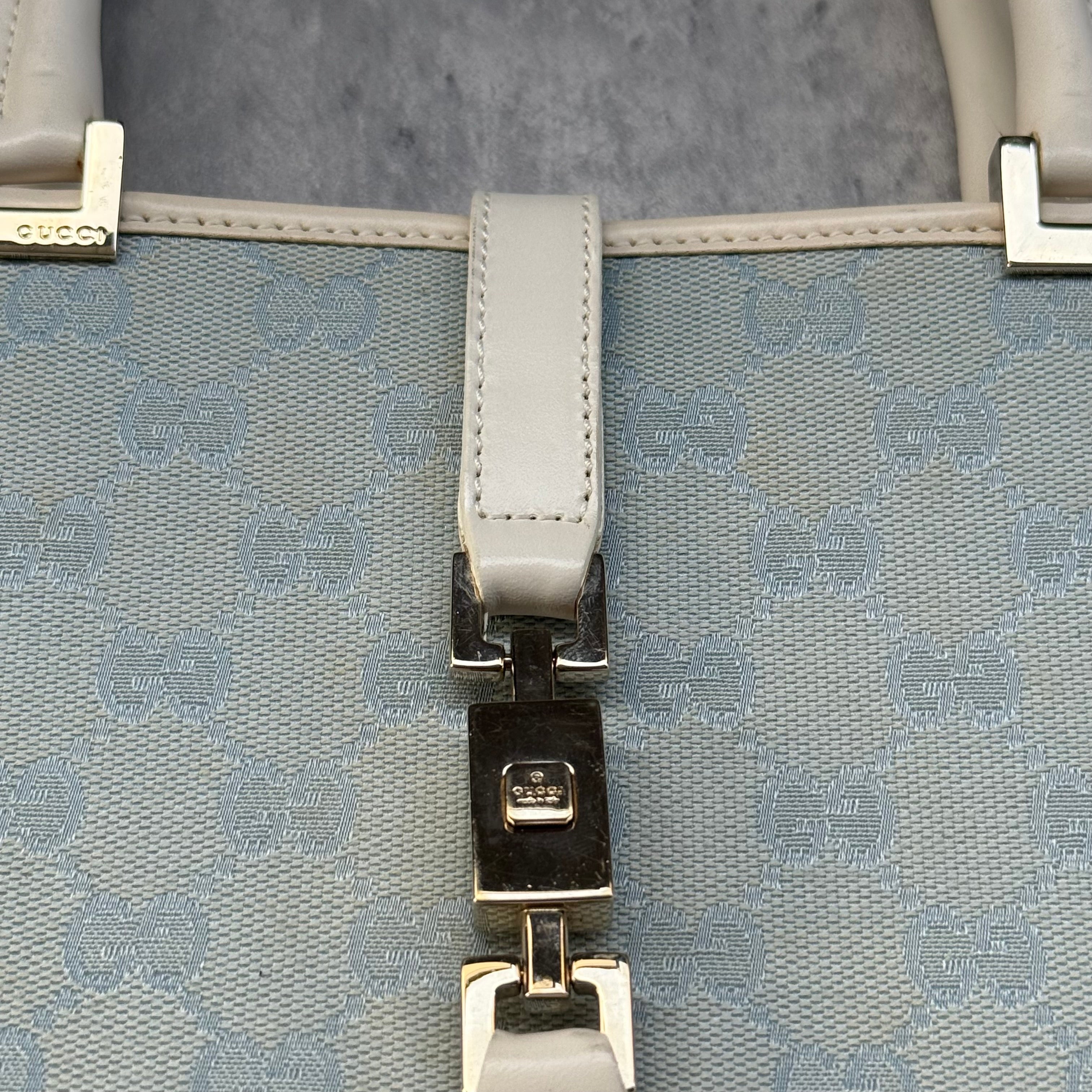 Gucci GG Monogram Jackie Shoulder Bag in light blue canvas with white leather trim, structured silhouette, and silver-tone piston lock.