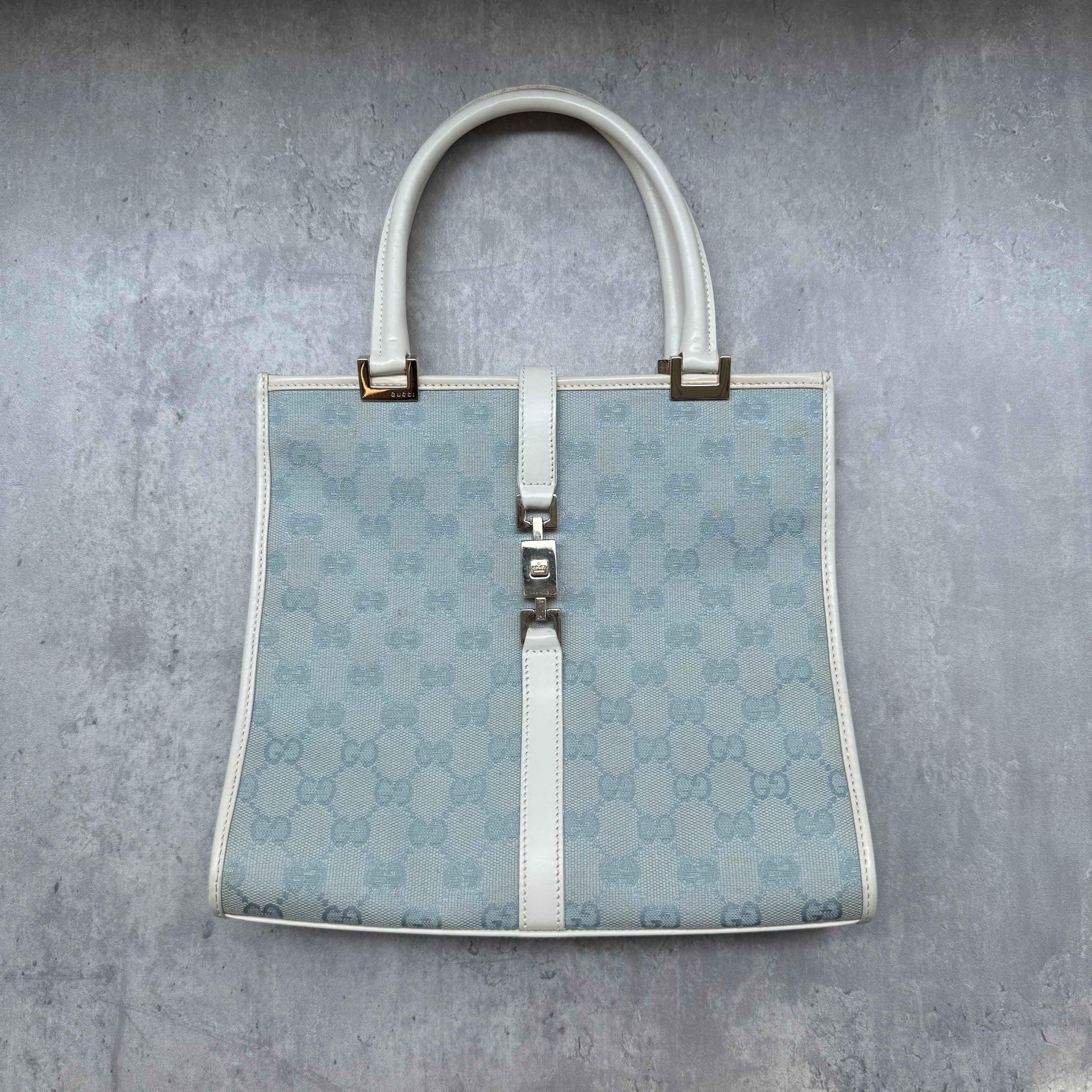 Gucci GG Monogram Jackie Shoulder Bag in light blue canvas with white leather trim, structured silhouette, and silver-tone piston lock.
