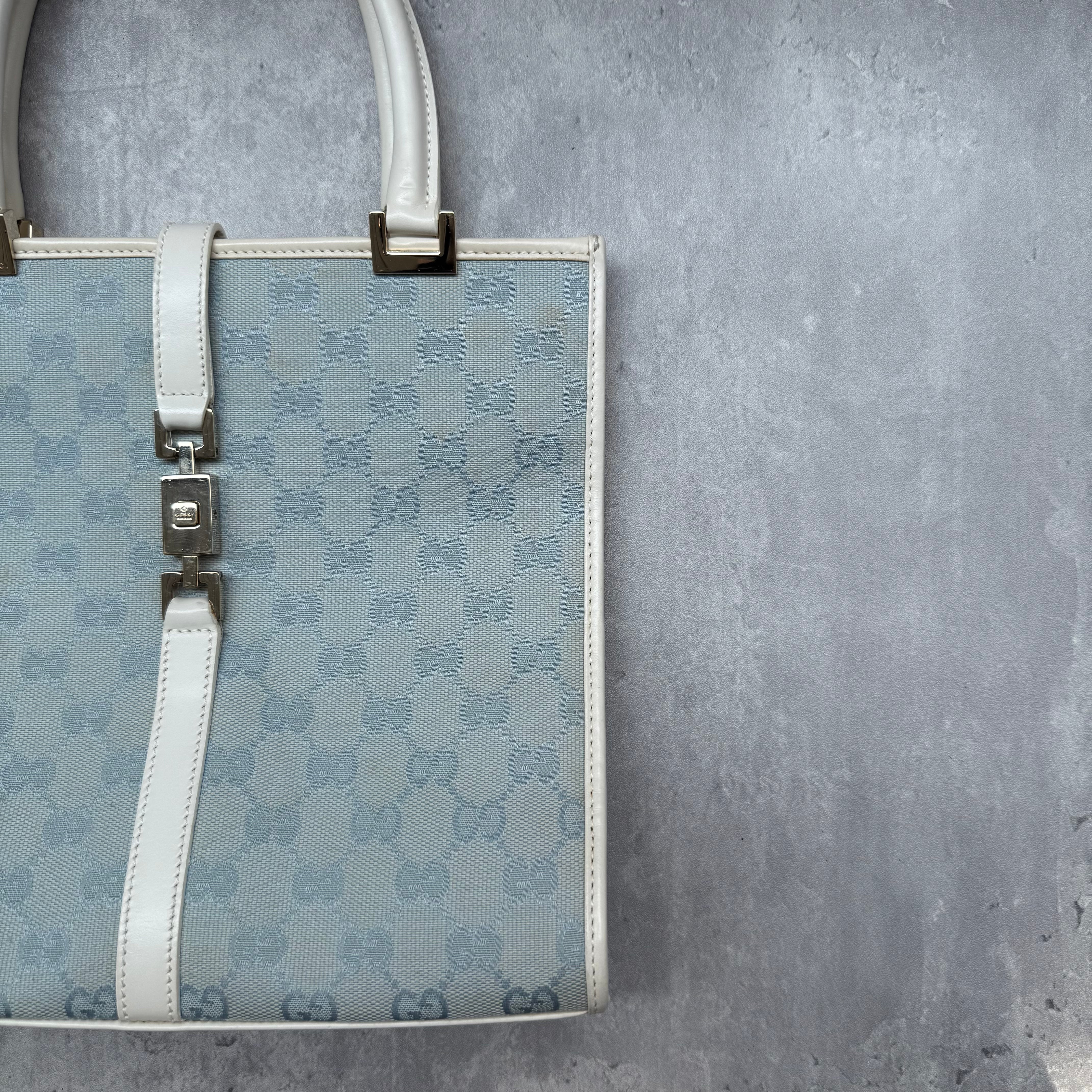Gucci GG Monogram Jackie Shoulder Bag in light blue canvas with white leather trim, structured silhouette, and silver-tone piston lock.