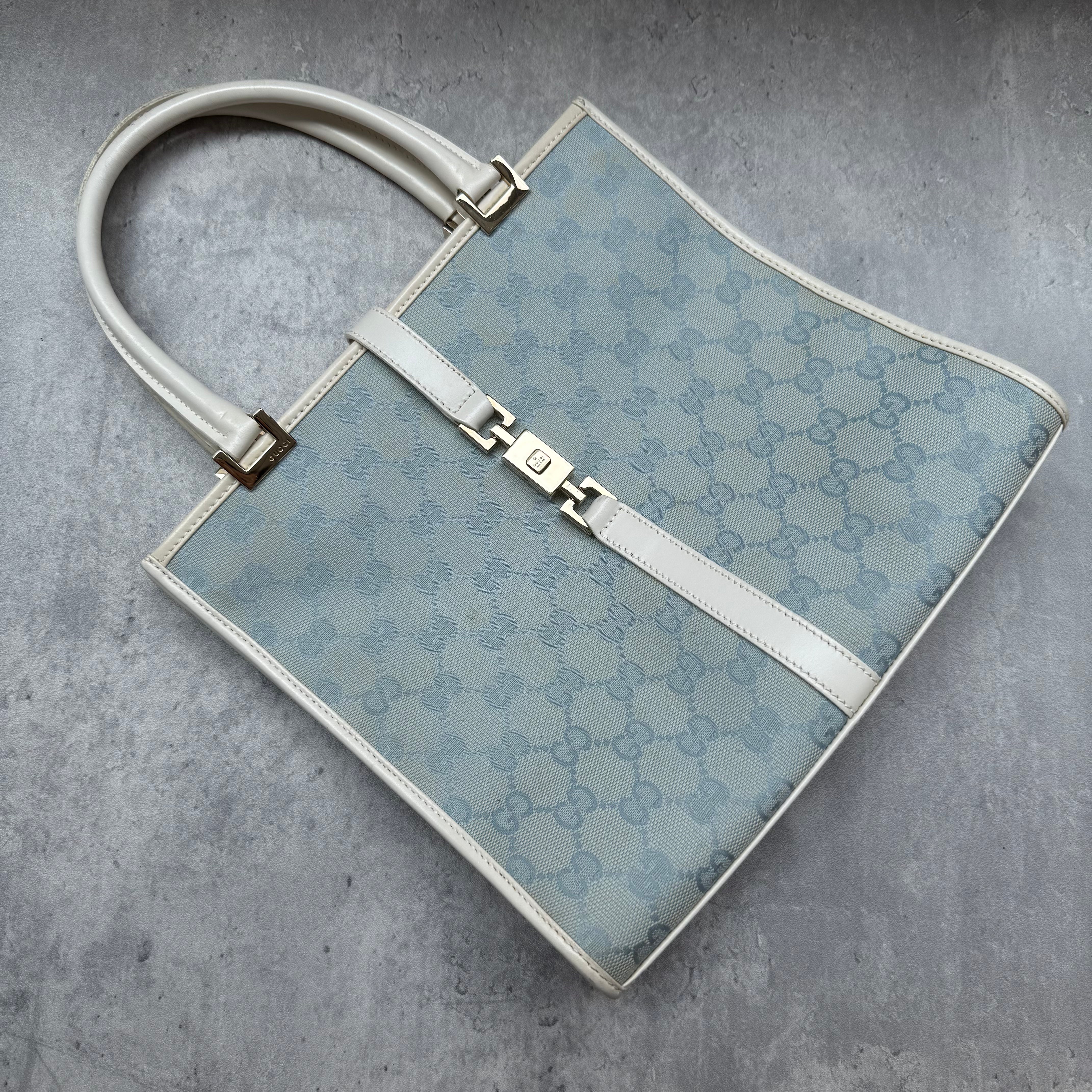 Gucci GG Monogram Jackie Shoulder Bag in light blue canvas with white leather trim, structured silhouette, and silver-tone piston lock.