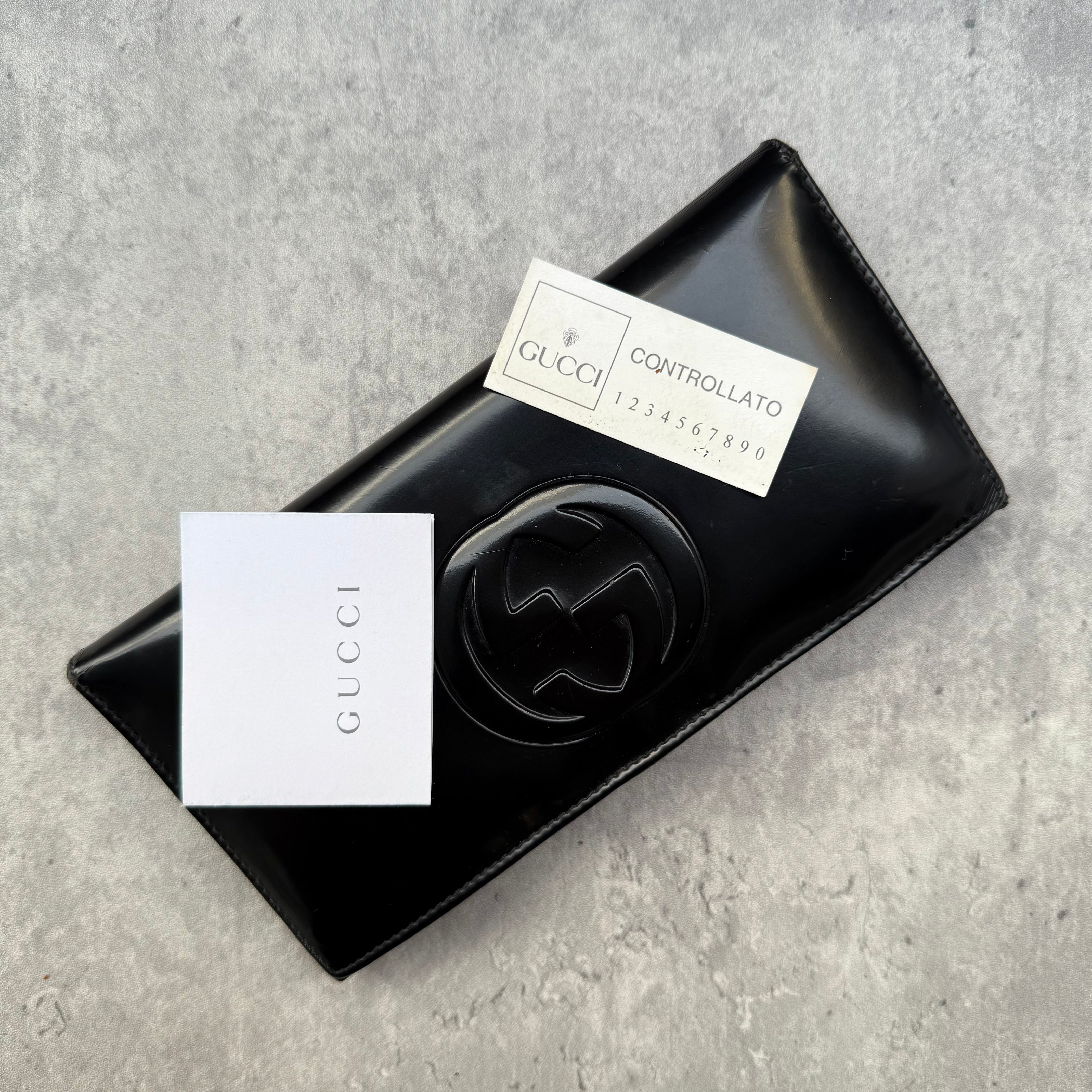 Gucci black patent leather bifold wallet with interlocking GG logo, original Gucci care card, and structured compartments