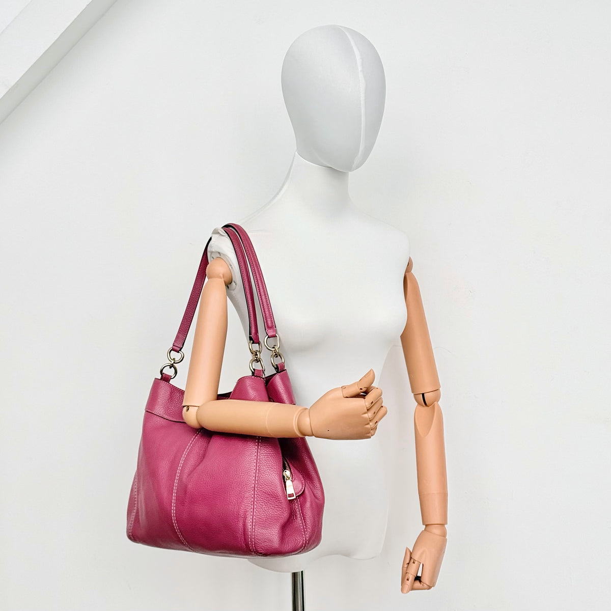 Coach Lexy Shoulder Bag in pink pebbled leather with gold hardware and dual straps, shown against a white background.