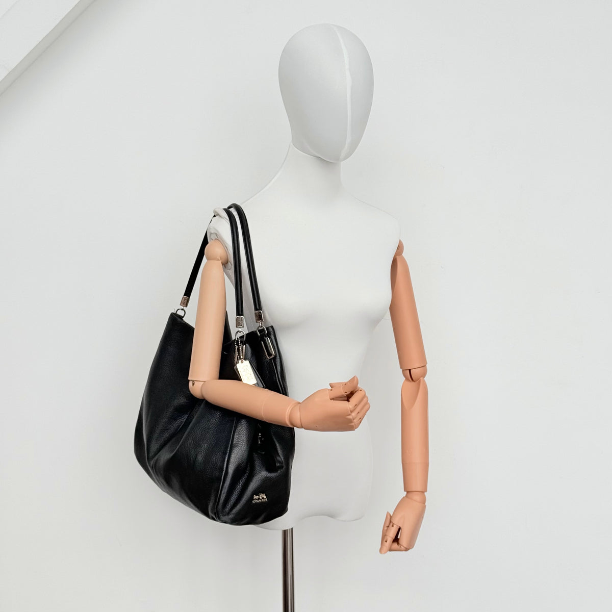 Coach Madison Phoebe Shoulder Bag in black grained leather with gold hardware and dual handles, shown against a white background.