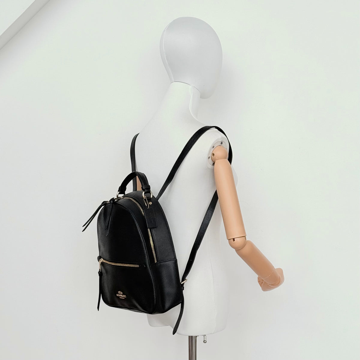 Coach Jordyn Leather Backpack in black grained leather with gold-tone hardware and minimal branding, photographed on white background.