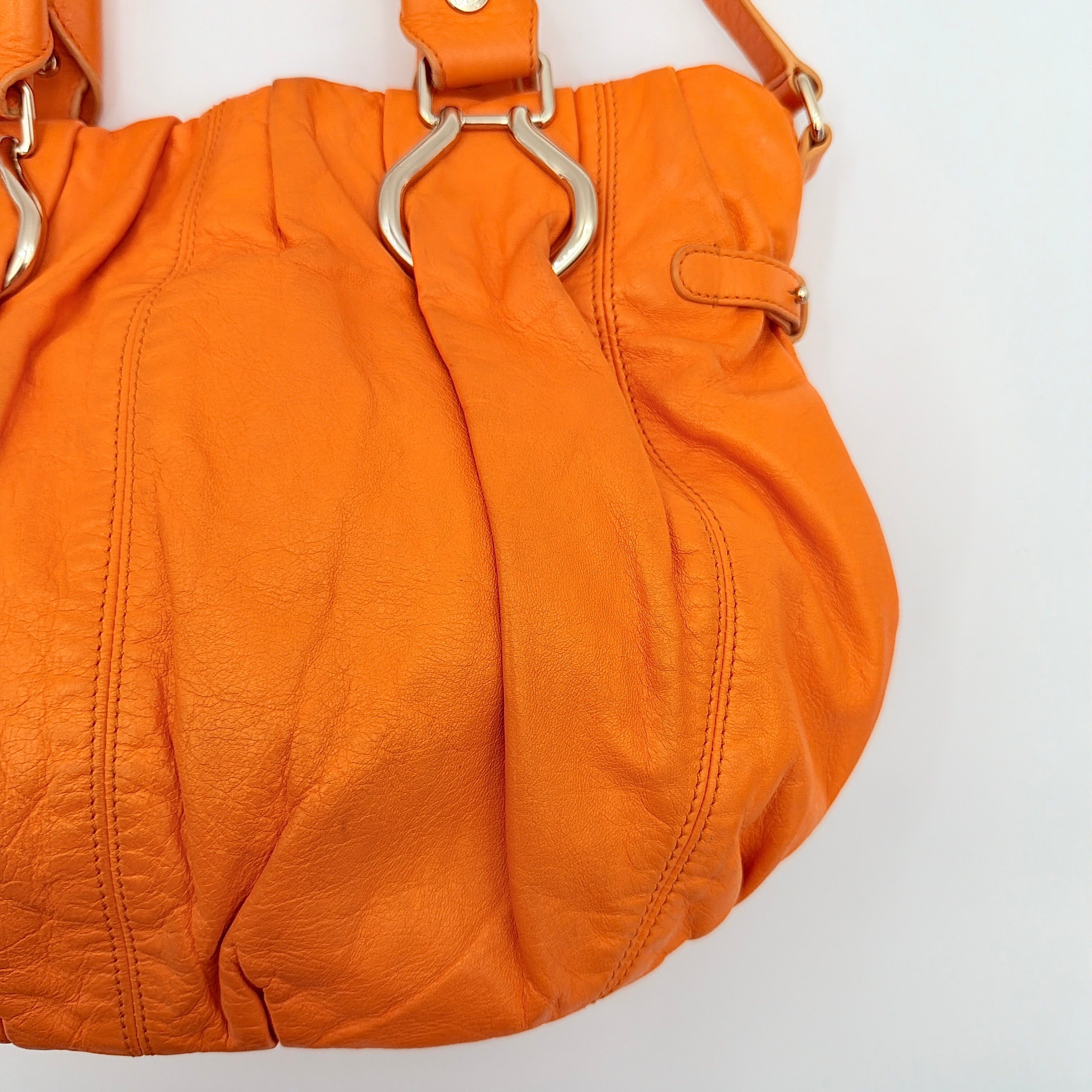 Celine 2Way Shoulder Bag in vibrant orange leather with silver-tone hardware and pleated detailing, shown with both top handles and an adjustable strap.