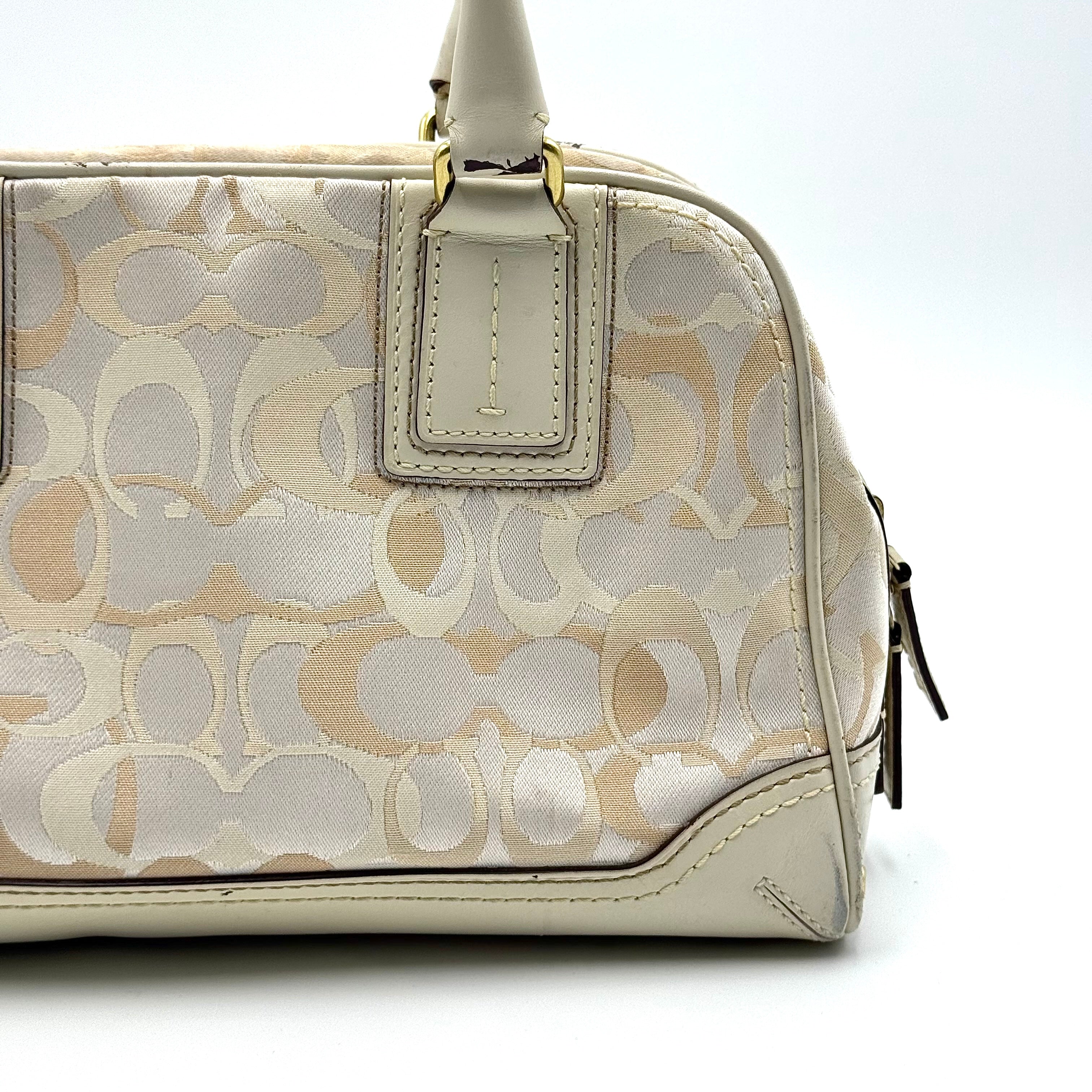 Coach Signature Canvas Satchel in ivory with dual rolled handles, monogram pattern and leather trim shown from the front against a clean background.