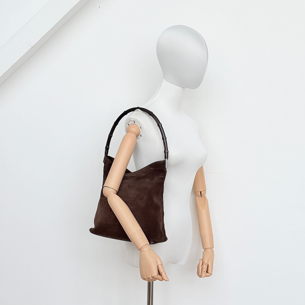 Gucci Bamboo Shoulder Bag in brown suede with a sculpted bamboo handle, photographed on a white background.