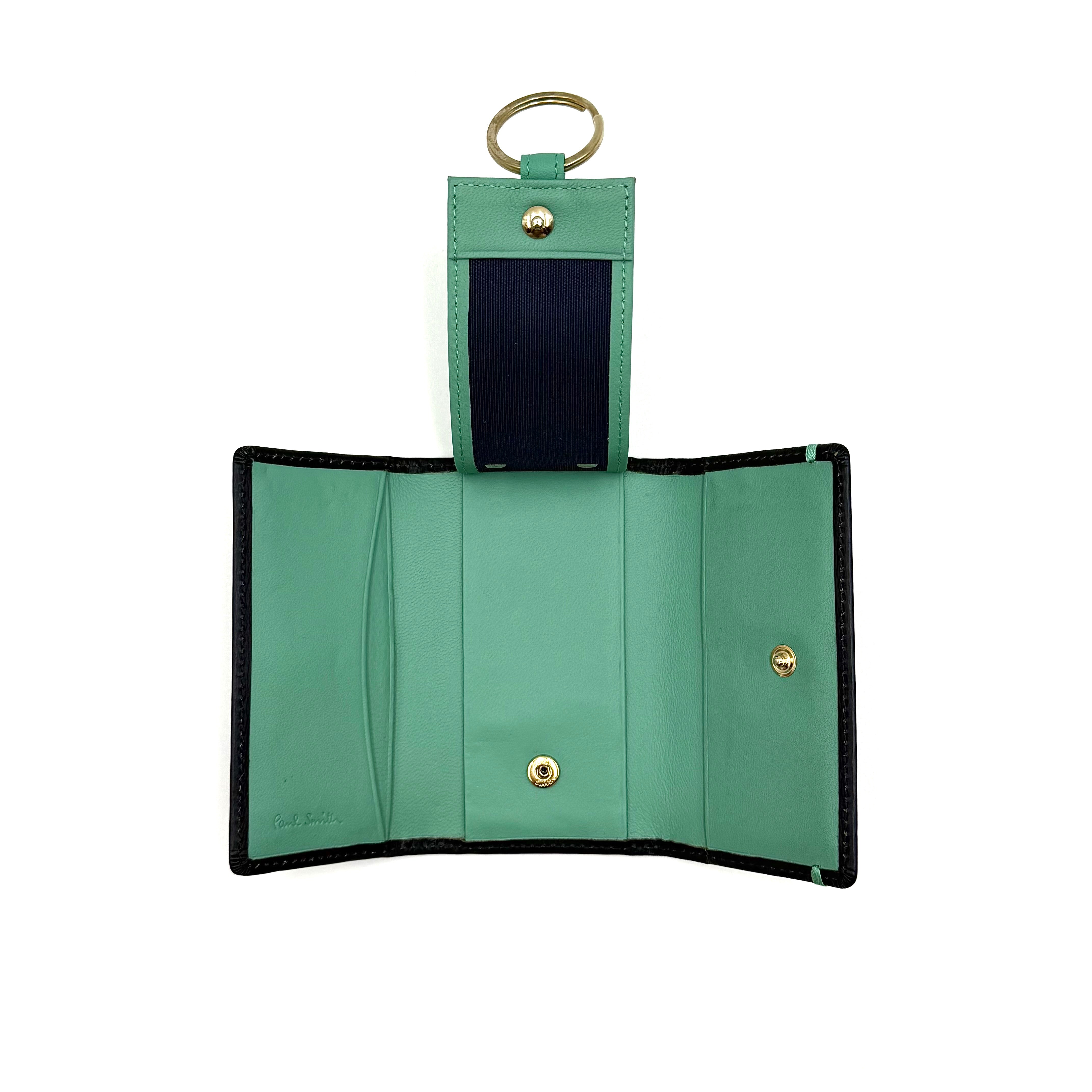 Paul Smith key case in grained black leather with Tiffany blue accents and silver logo, displayed on a white background.