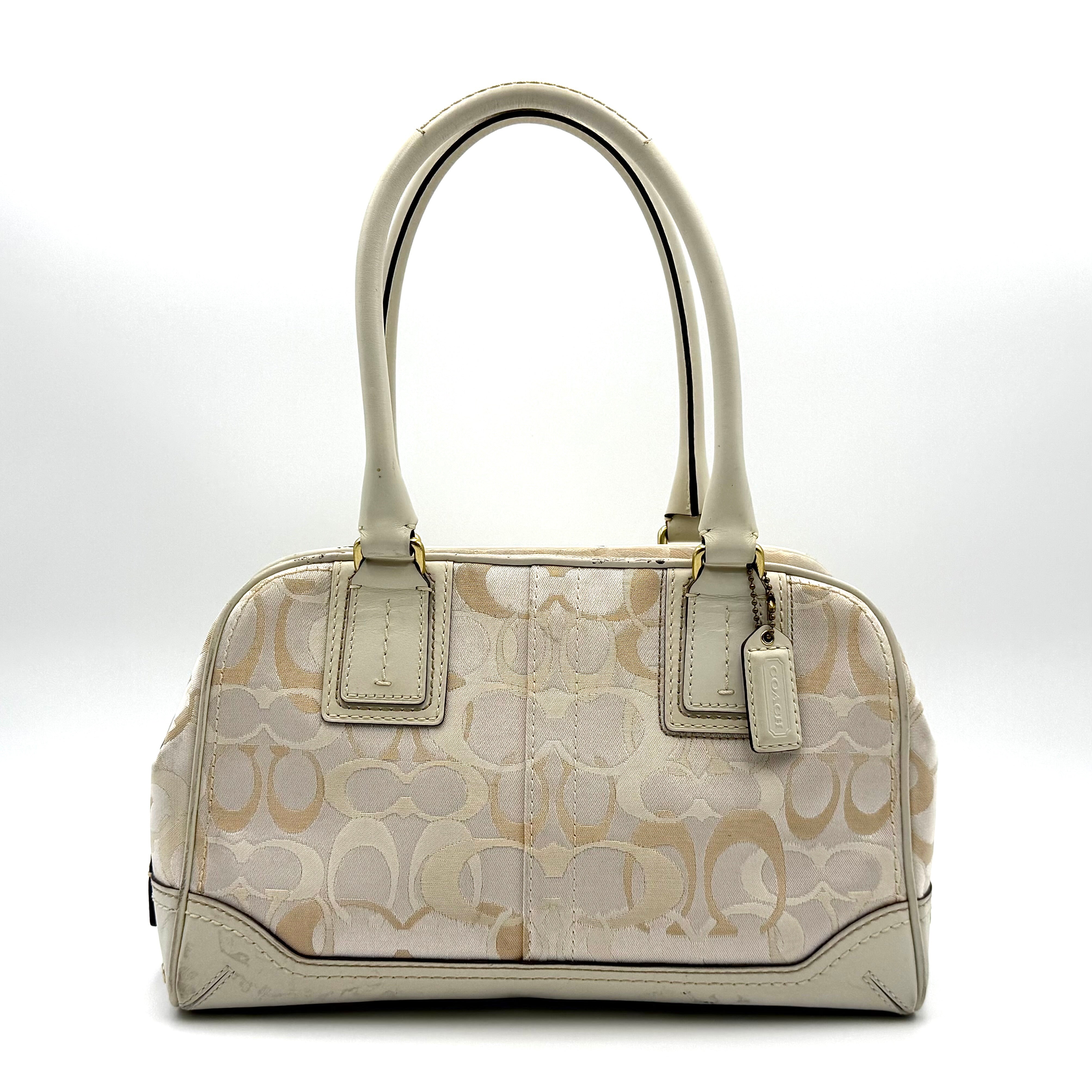 Coach Signature Canvas Satchel in ivory with dual rolled handles, monogram pattern and leather trim shown from the front against a clean background.