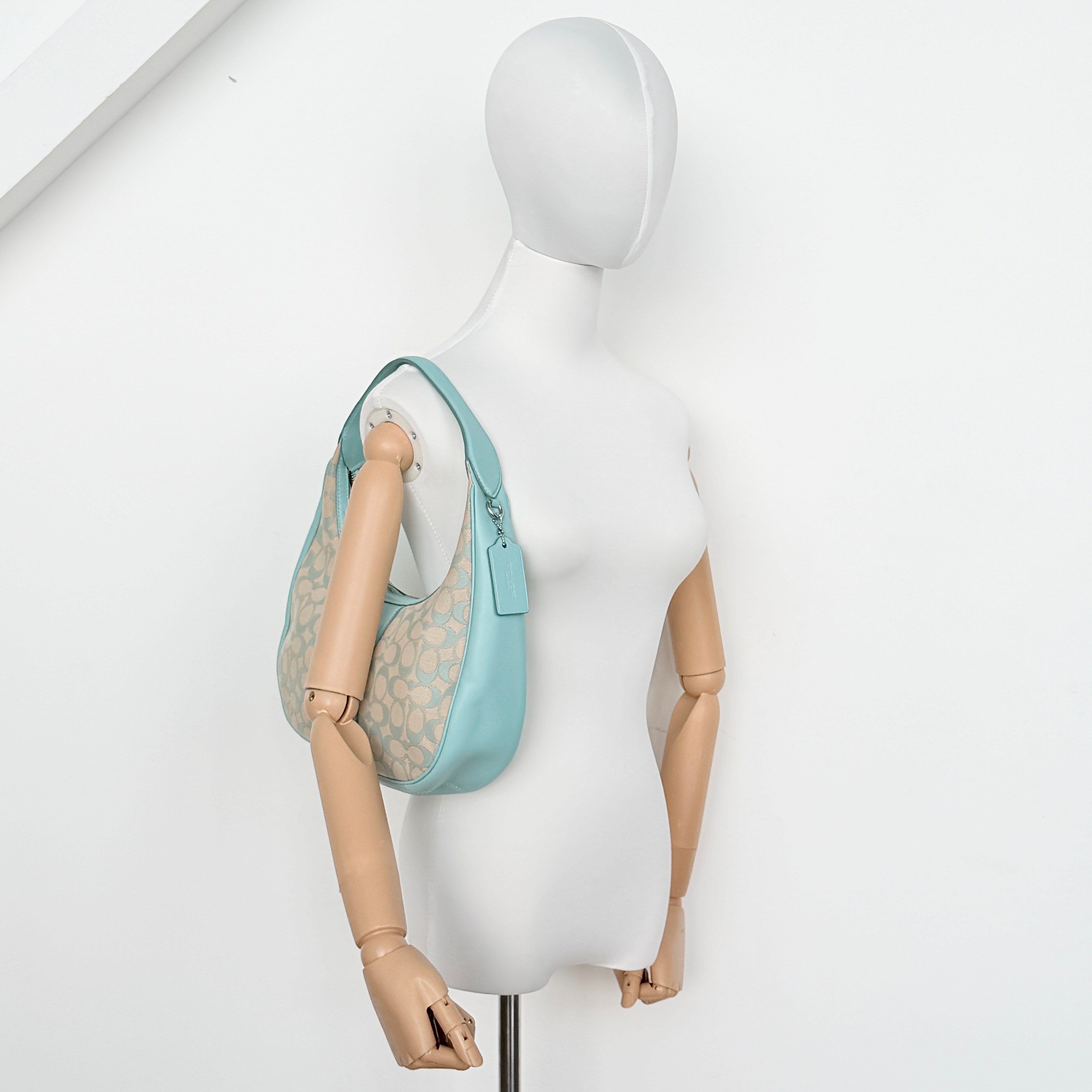 Coach Signature Carmen Shoulder Bag in beige and blue canvas with powder blue leather trim and silver hardware, photographed on white background.