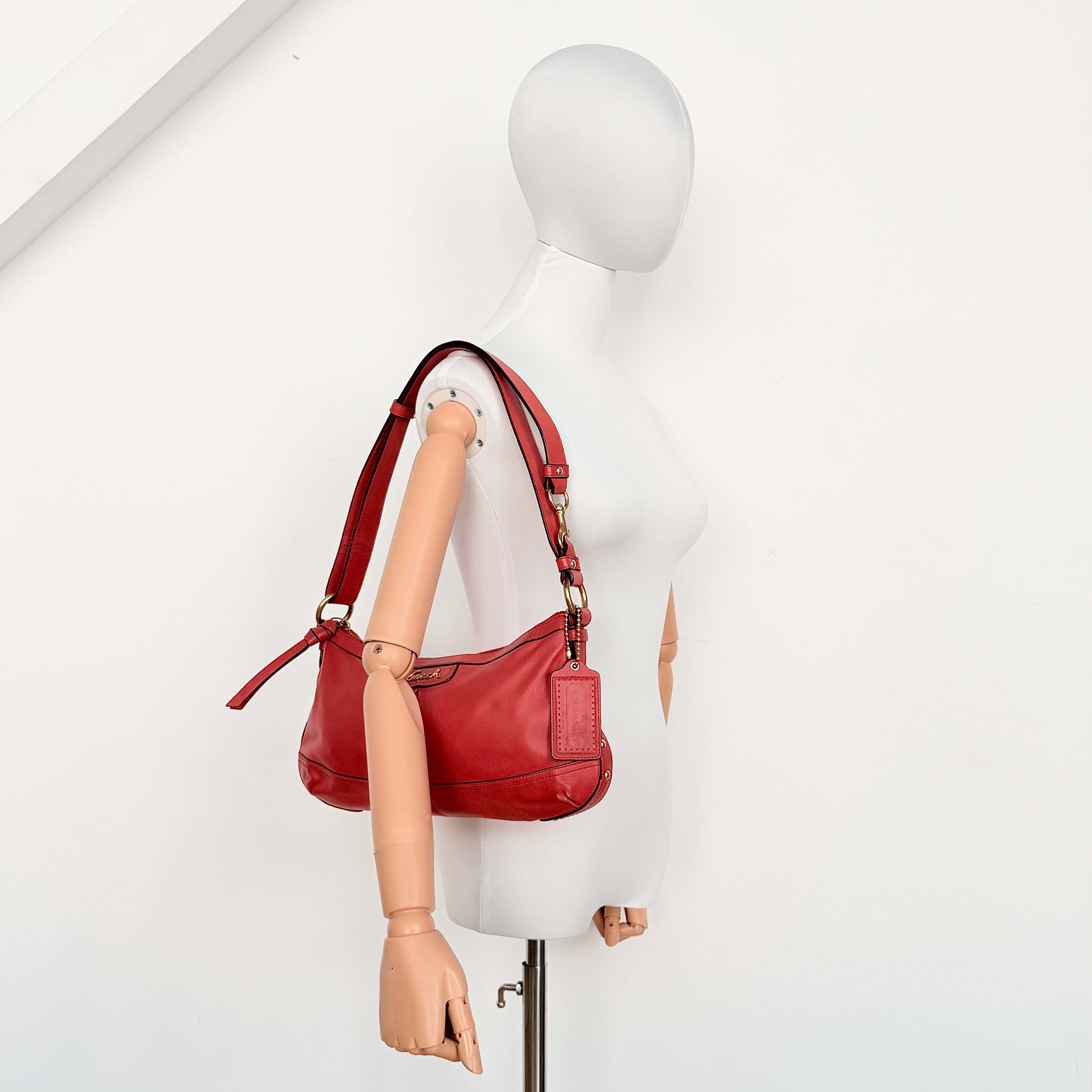 Coach 2Way Park Shoulder Bag in orange leather with gold hardware and adjustable strap, displayed against a white background.