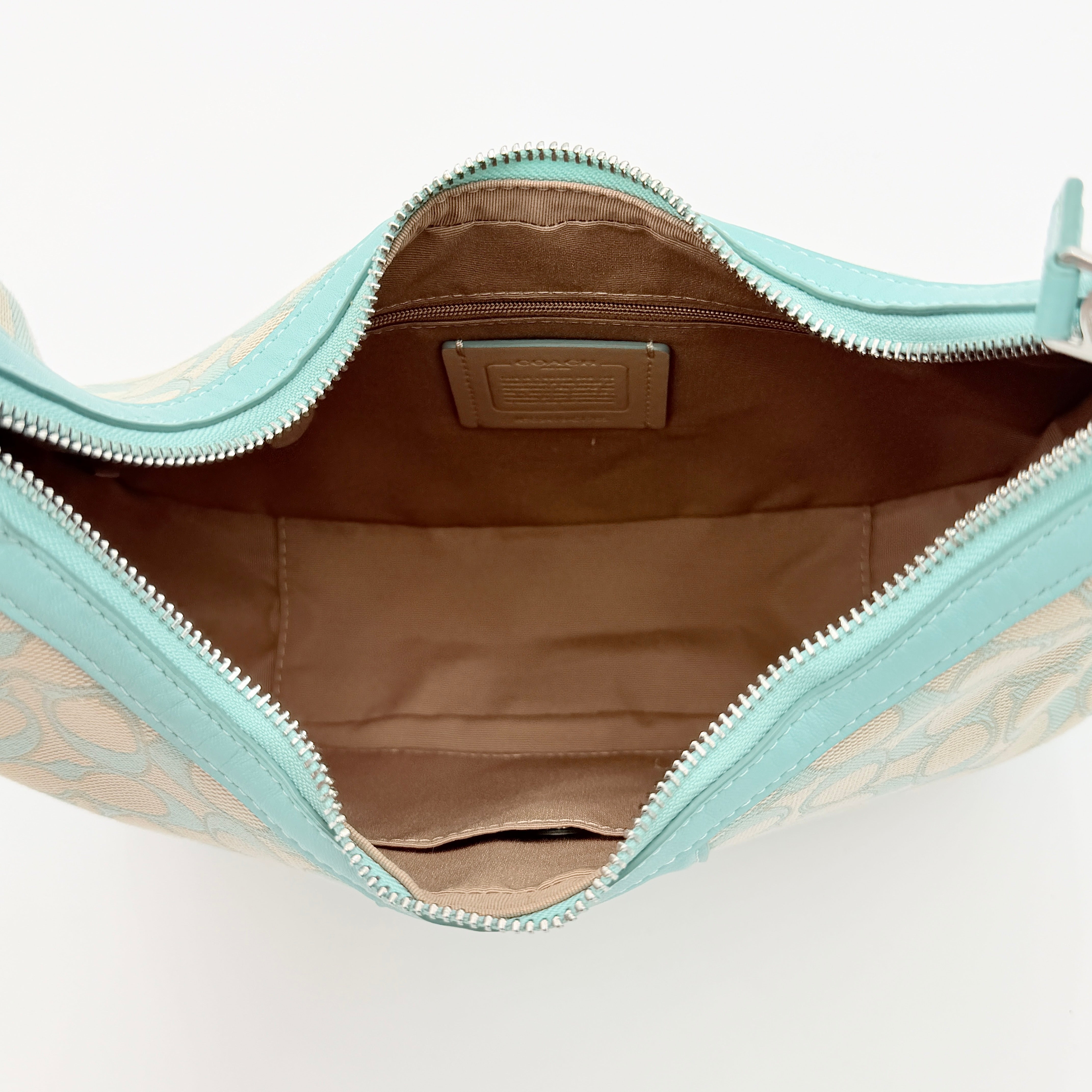 Coach Signature Carmen Shoulder Bag in beige and blue canvas with powder blue leather trim and silver hardware, photographed on white background.