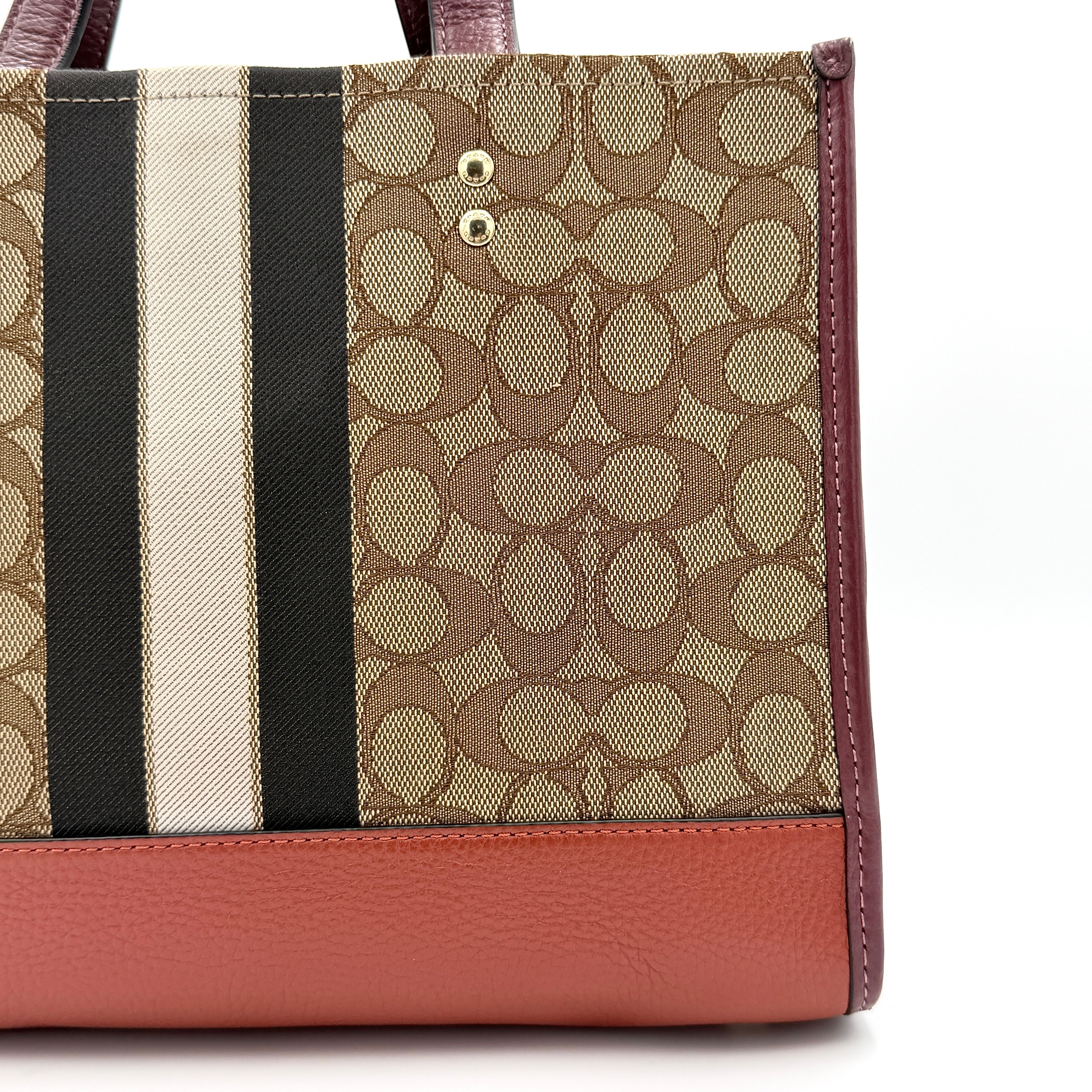 Coach 2Way Signature 22 Dempsey Tote in brown jacquard and burgundy leather with orange logo patch, shown with detachable strap.