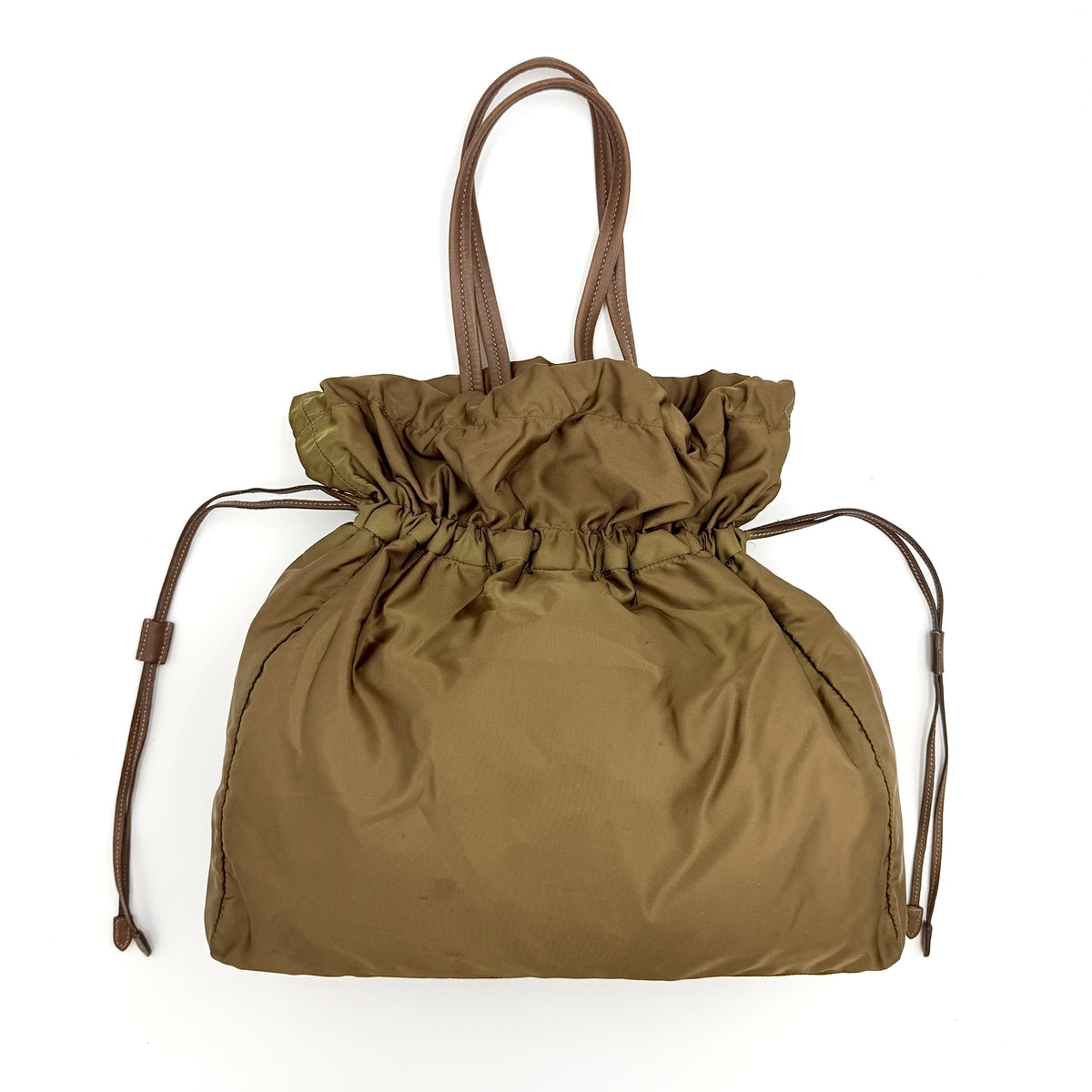 Prada Tessuto brown nylon drawstring shoulder bag with leather handles and gold logo detail, photographed against a white background.