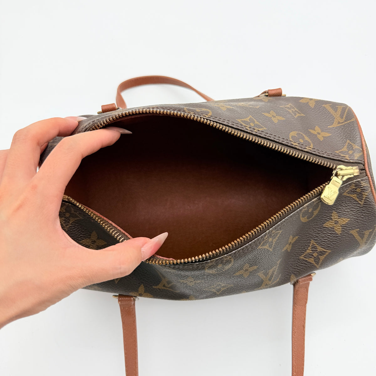 Louis Vuitton Papillon 26 in monogram canvas with leather handles and gold zipper, shown on a white background.