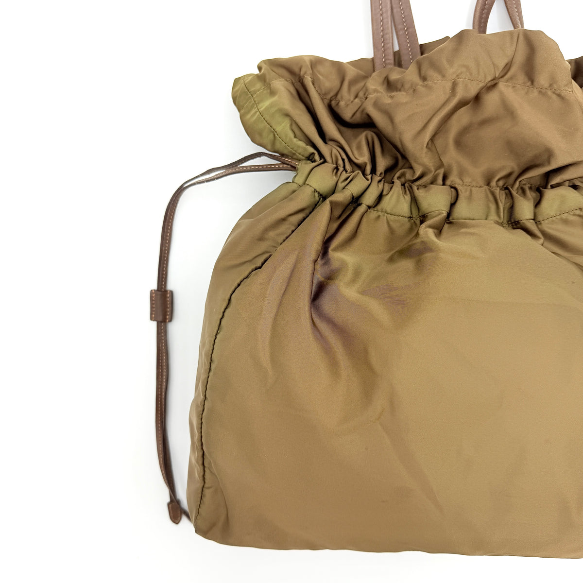 Prada Tessuto brown nylon drawstring shoulder bag with leather handles and gold logo detail, photographed against a white background.