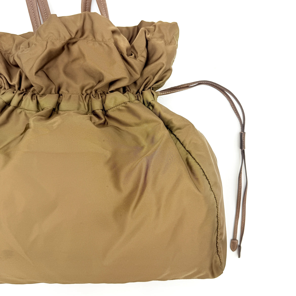 Prada Tessuto brown nylon drawstring shoulder bag with leather handles and gold logo detail, photographed against a white background.