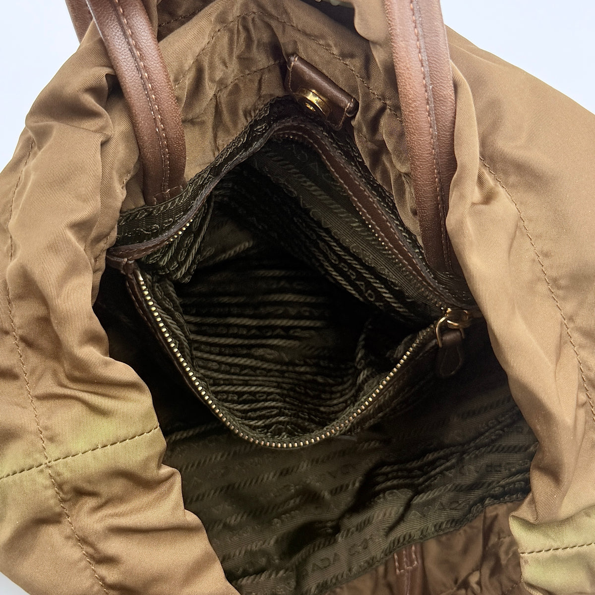 Prada Tessuto brown nylon drawstring shoulder bag with leather handles and gold logo detail, photographed against a white background.