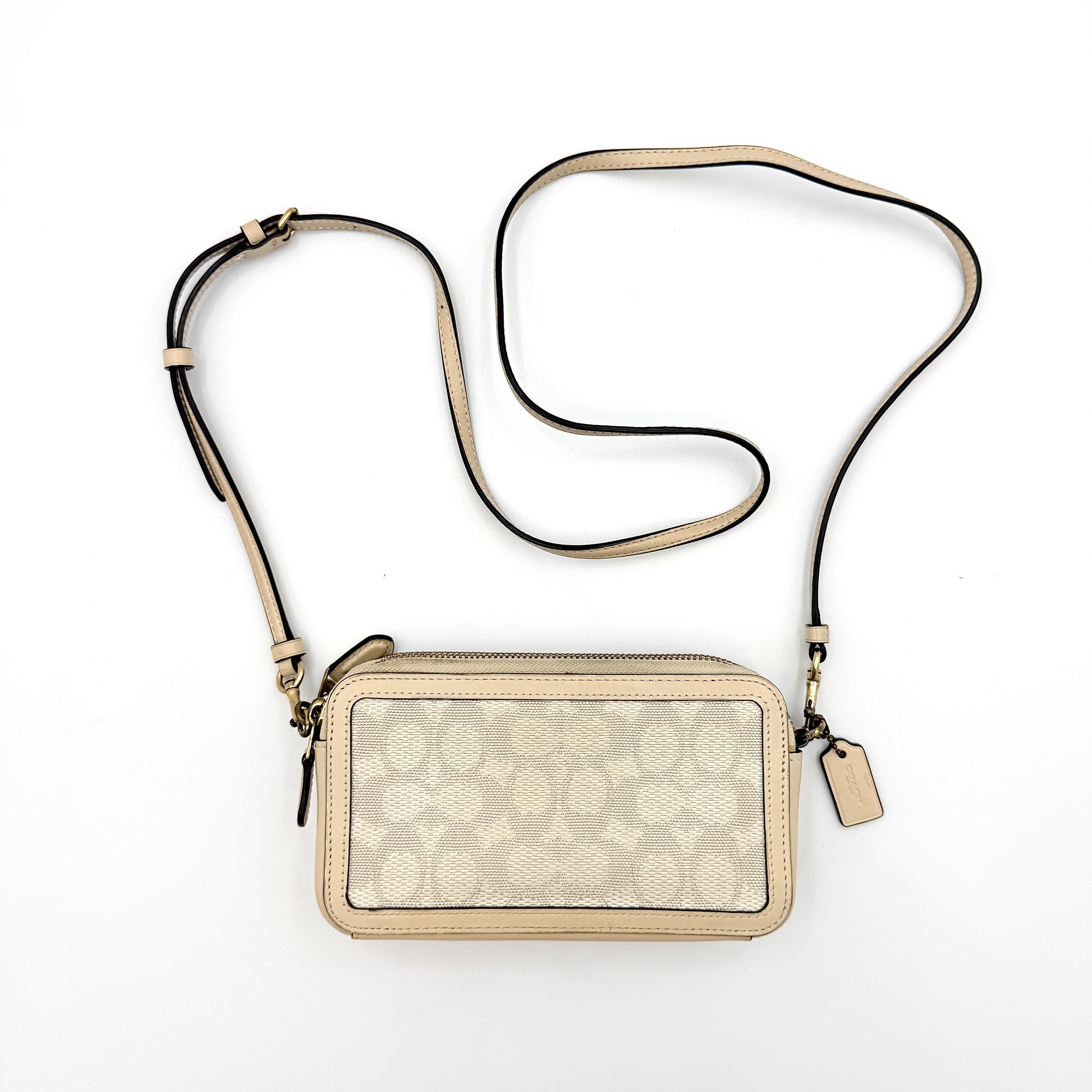 Coach Signature Kira Crossbody Bag in beige and white jacquard with leather trim and adjustable strap displayed against a white background.