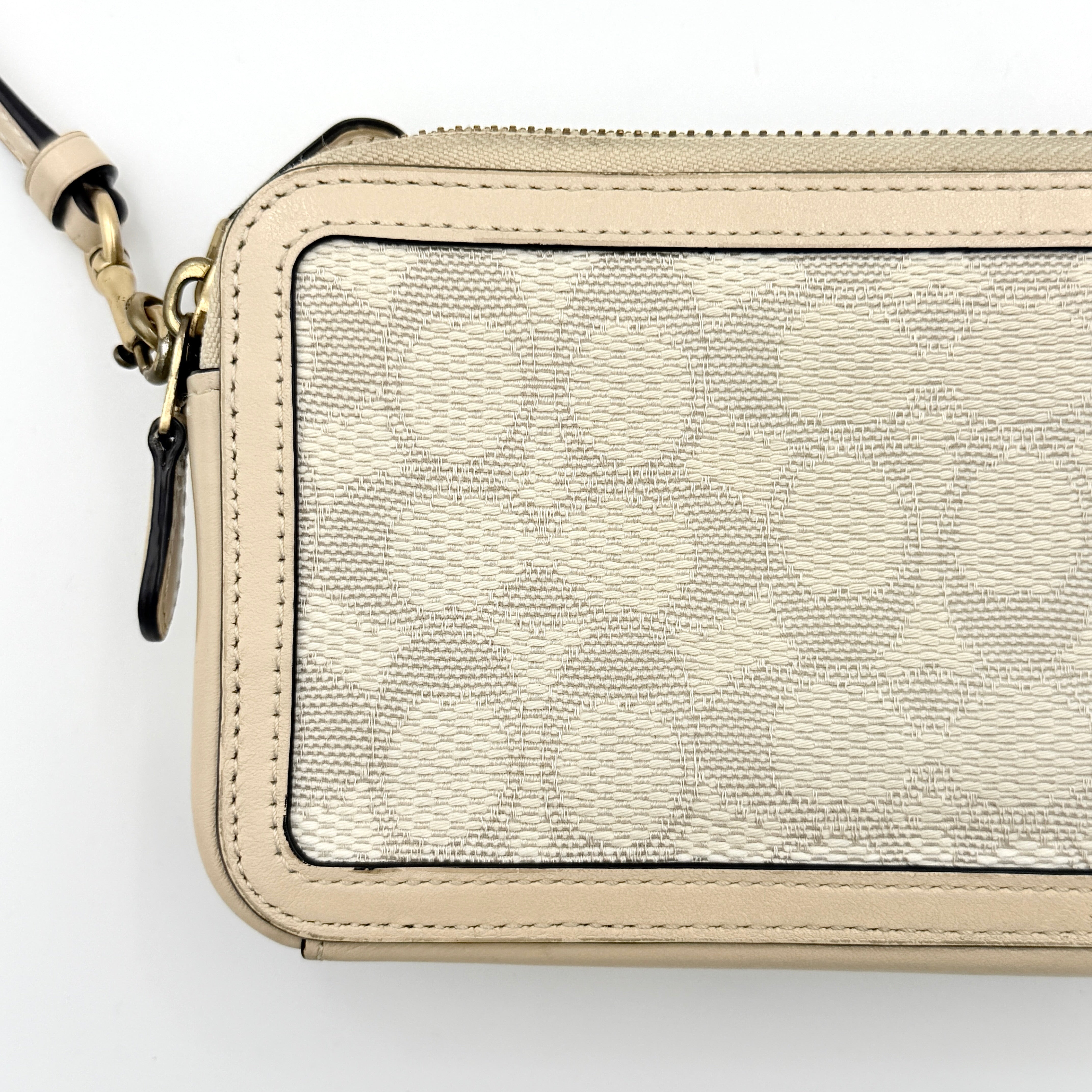 Coach Signature Kira Crossbody Bag in beige and white jacquard with leather trim and adjustable strap displayed against a white background.