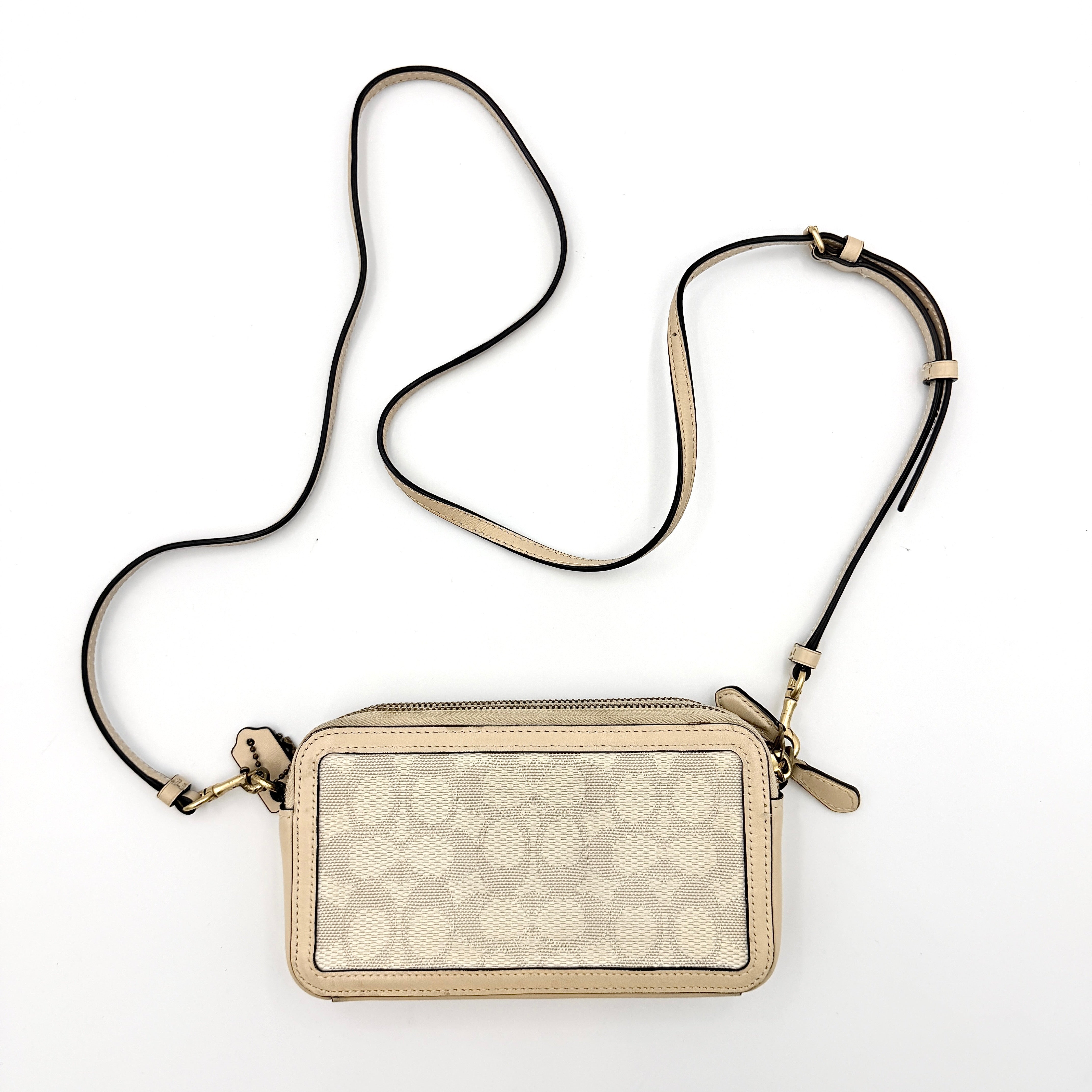 Coach Signature Kira Crossbody Bag in beige and white jacquard with leather trim and adjustable strap displayed against a white background.