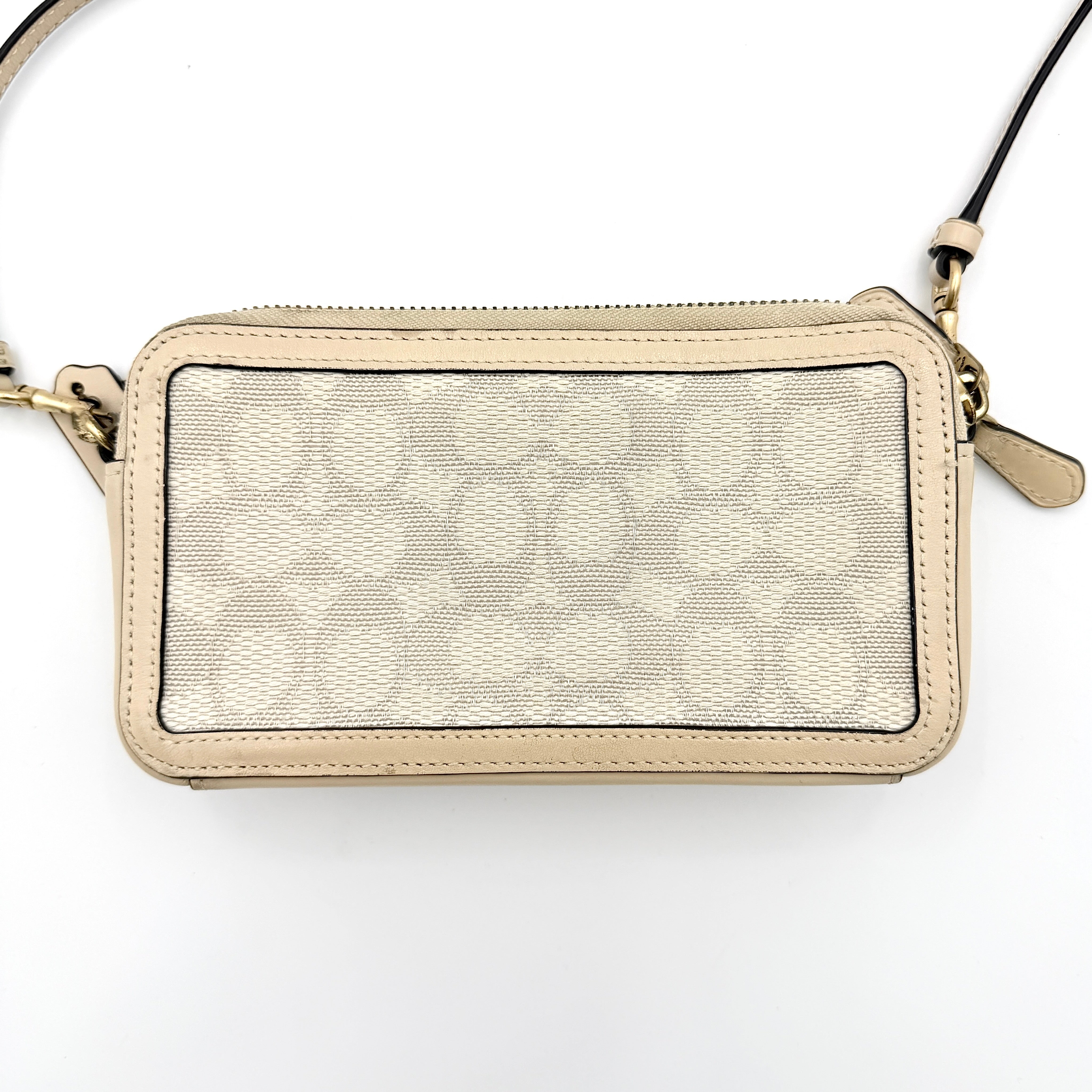 Coach Signature Kira Crossbody Bag in beige and white jacquard with leather trim and adjustable strap displayed against a white background.