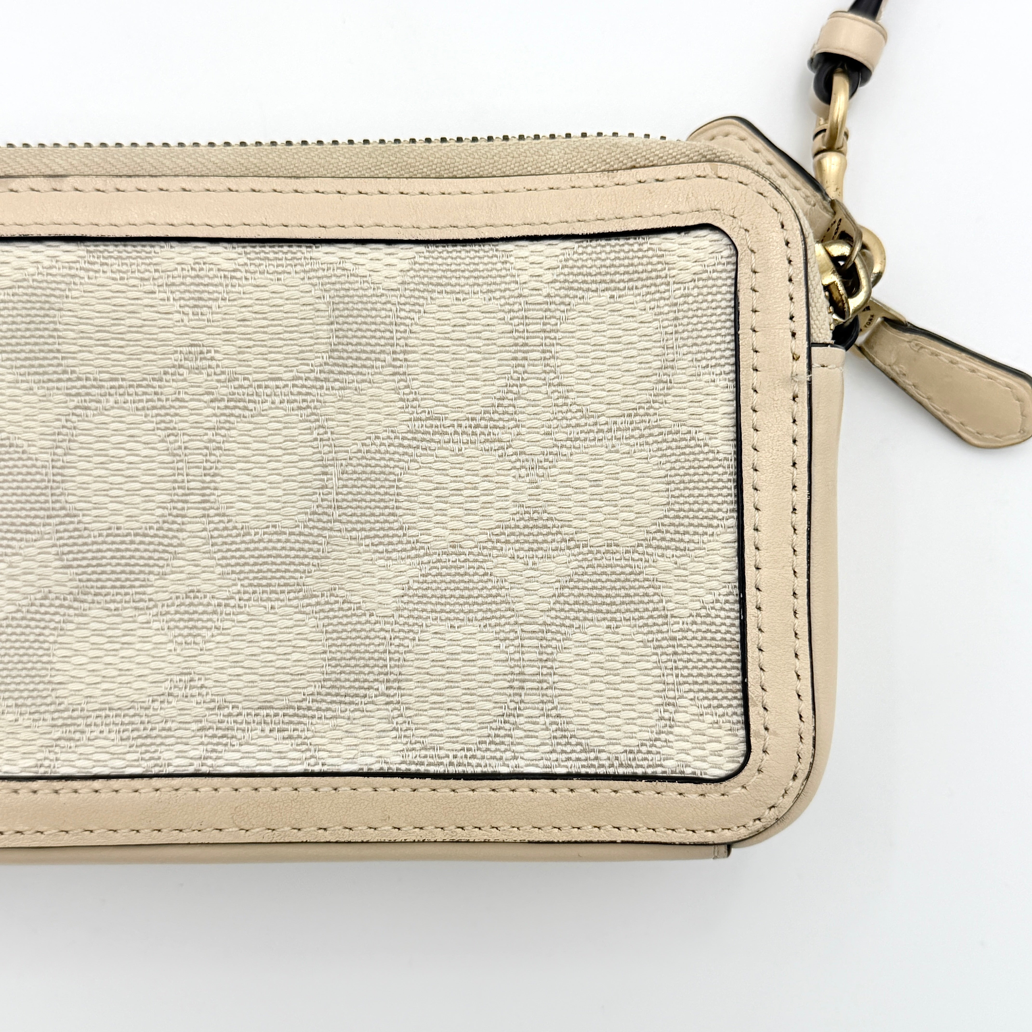 Coach Signature Kira Crossbody Bag in beige and white jacquard with leather trim and adjustable strap displayed against a white background.
