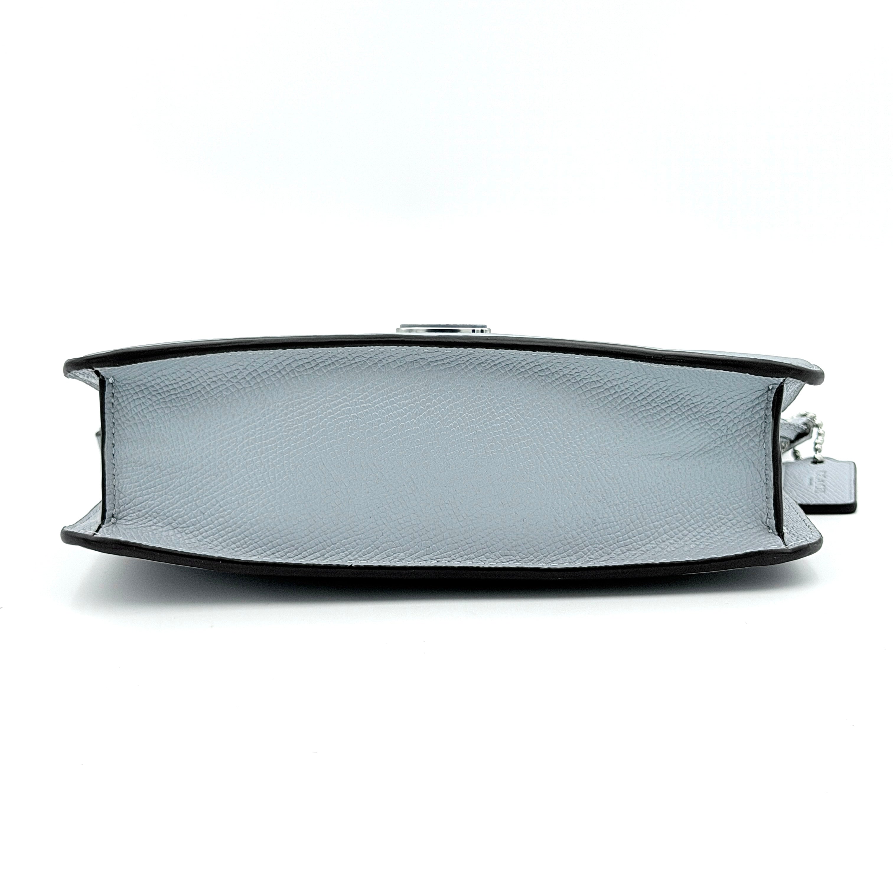 Sky blue Coach grained leather shoulder bag with silver-tone C plaque and short strap, displayed against a white background.