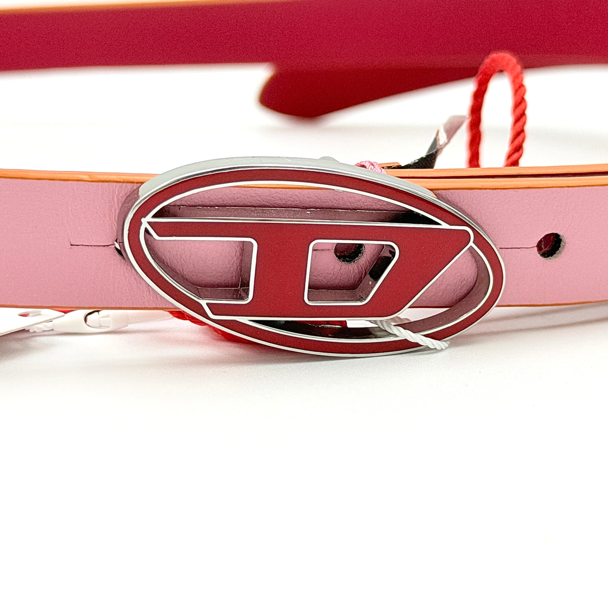 Diesel B-1DR pink leather belt with a silver and red D logo buckle, shown coiled on a white background.