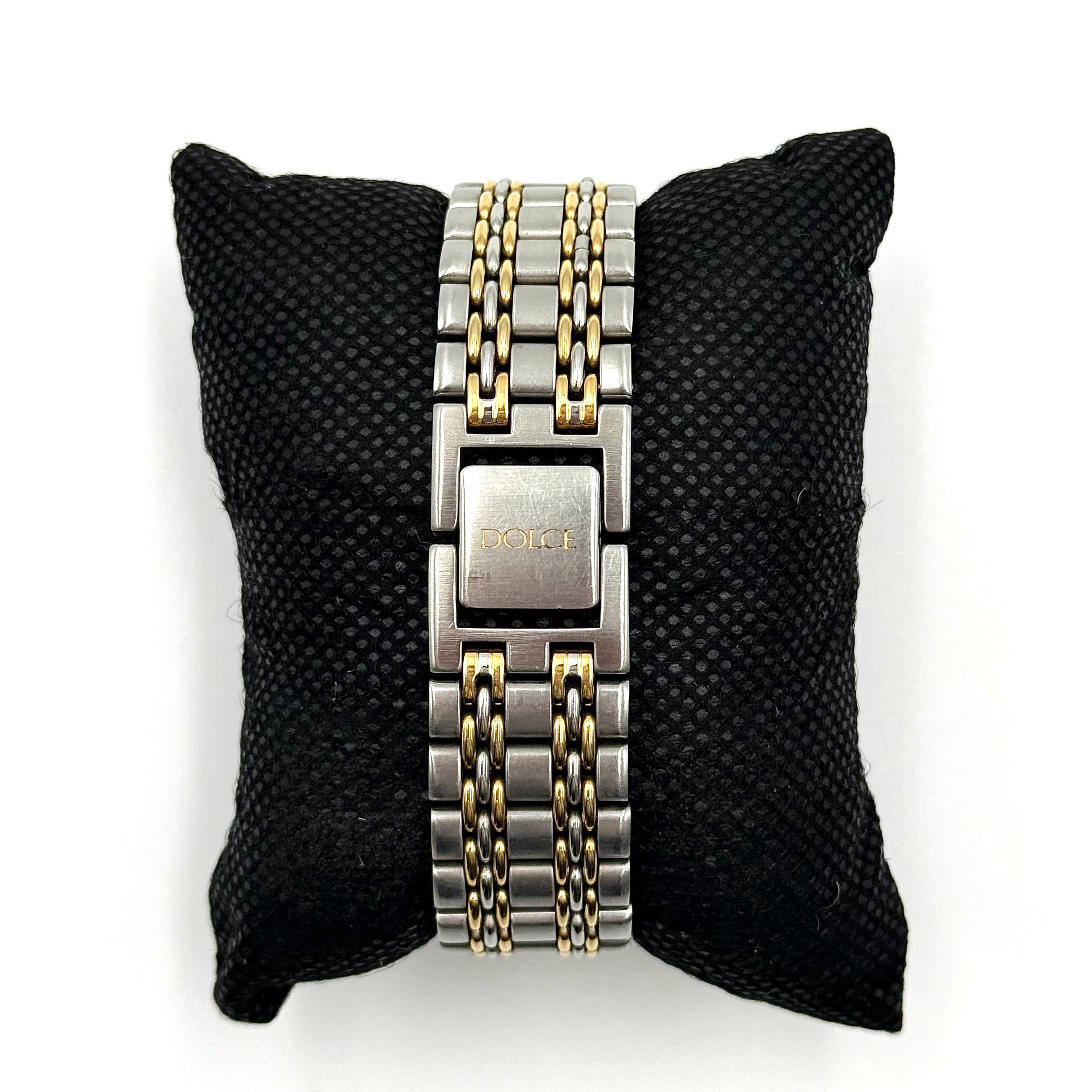 Seiko Dolce 5E31-6B90 watch in stainless steel with gold-tone accents and a cream dial, displayed on a black cushion.